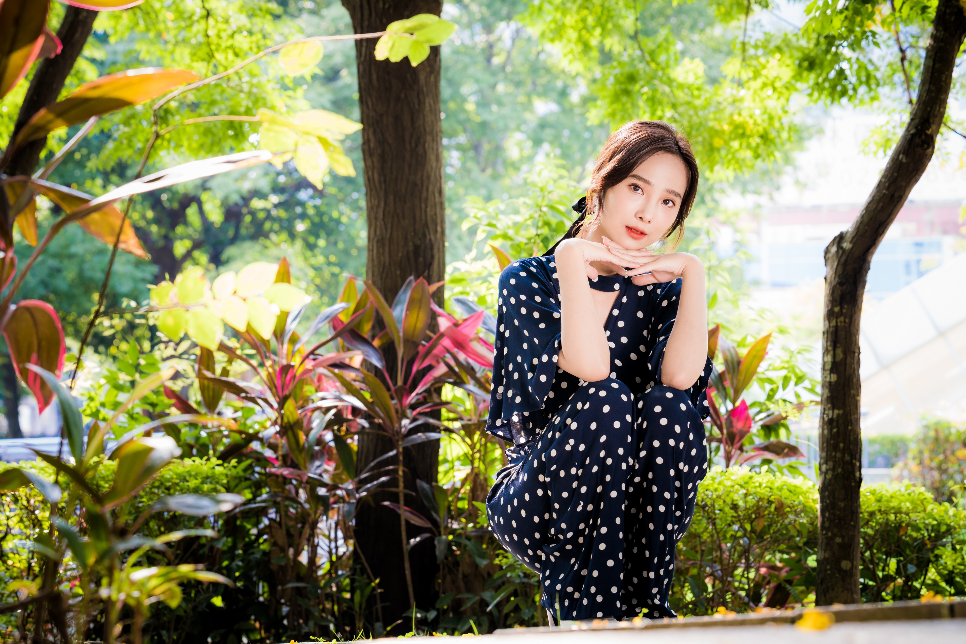 Asian woman in polka dot dress in garden HD Wallpaper