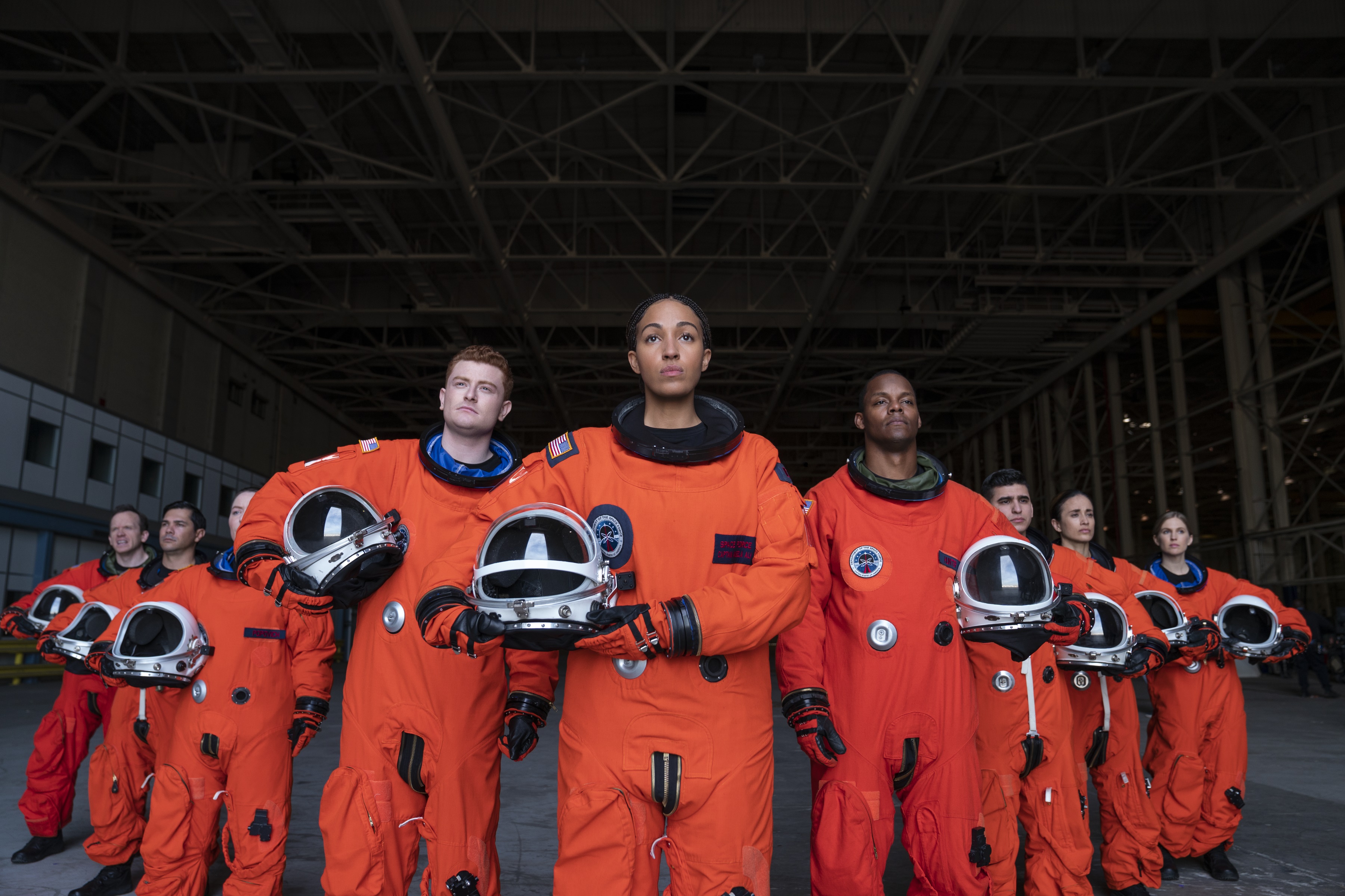 Astronauts in orange suits holding helmets HD Wallpaper