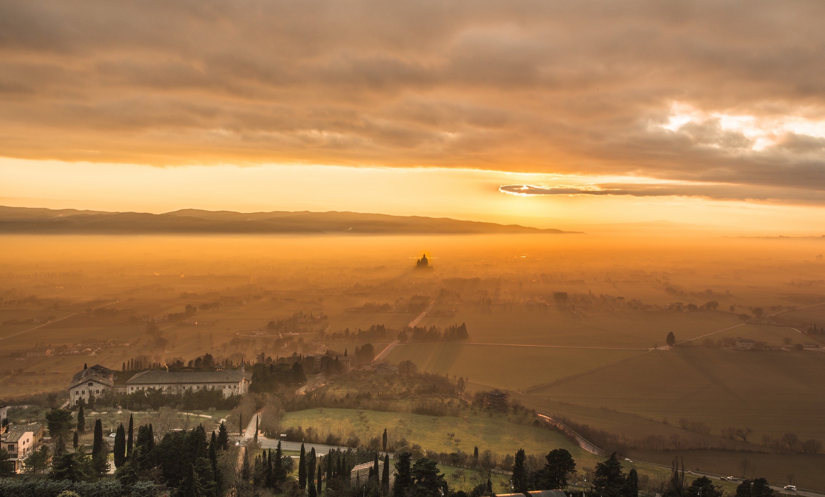 Sunrise over a misty valley with a distant church HD Wallpaper
