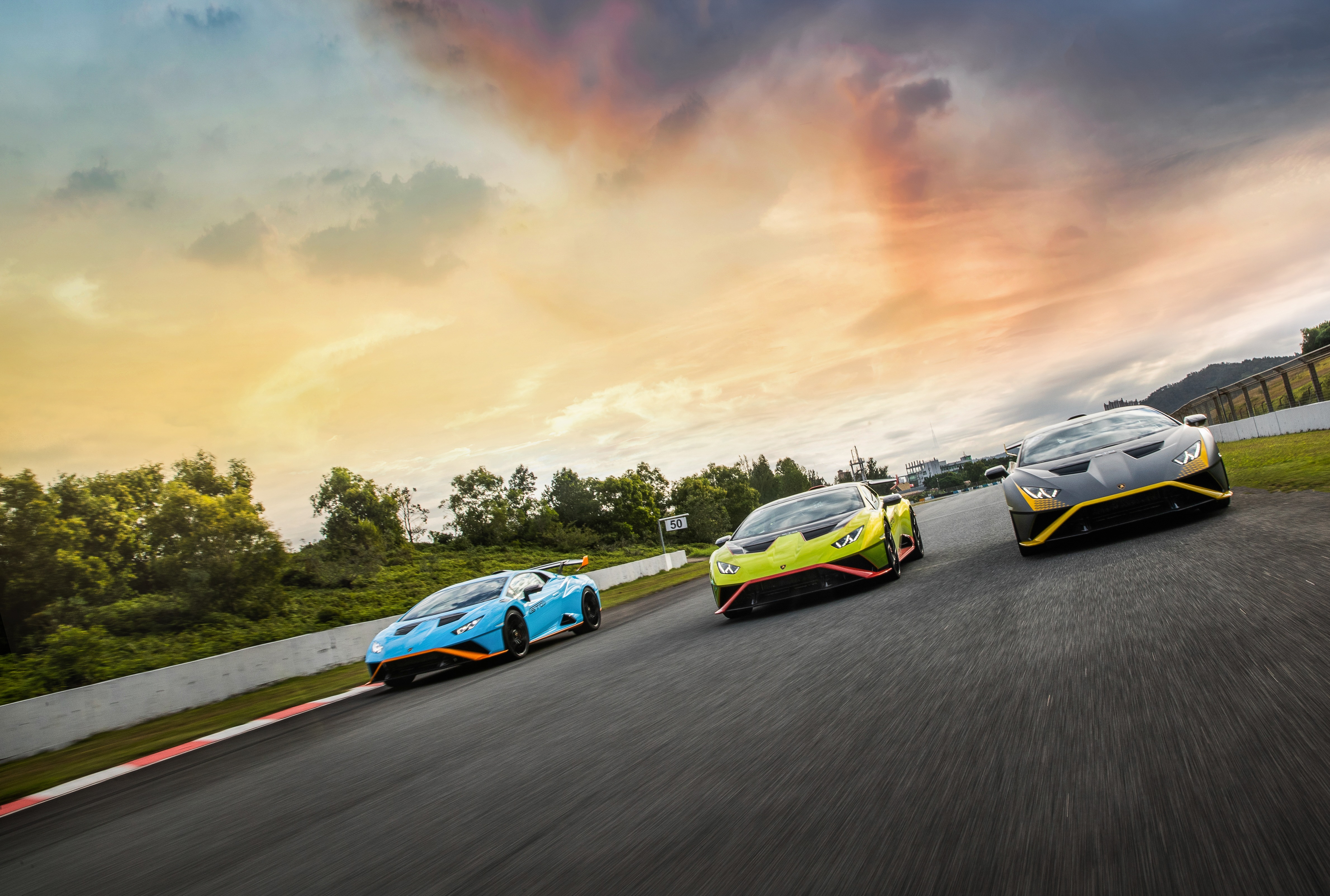 Three Lamborghini Huracán STO cars on a racetrack HD Wallpaper