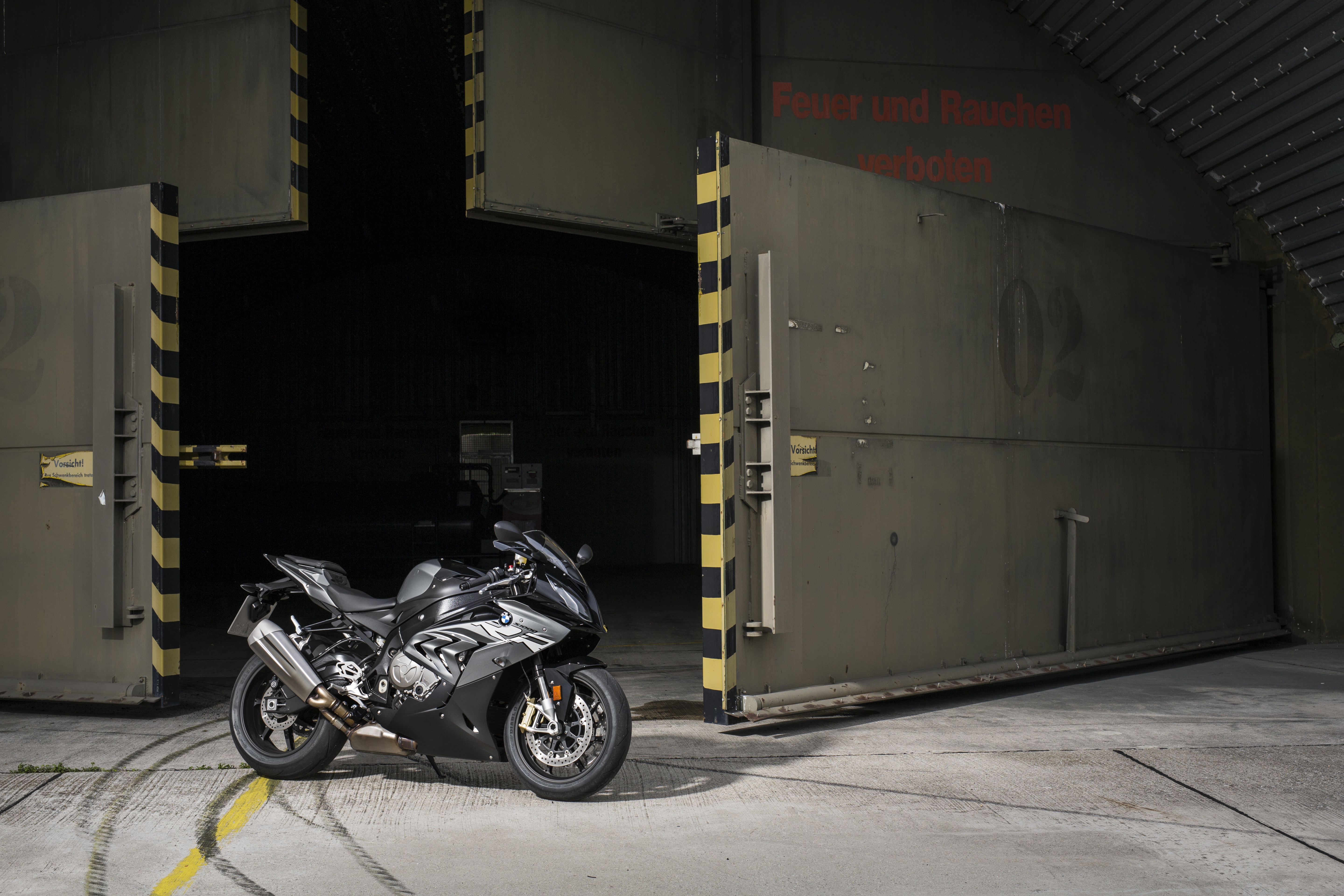 Black BMW S1000RR motorcycle in front of hangar doors HD Wallpaper