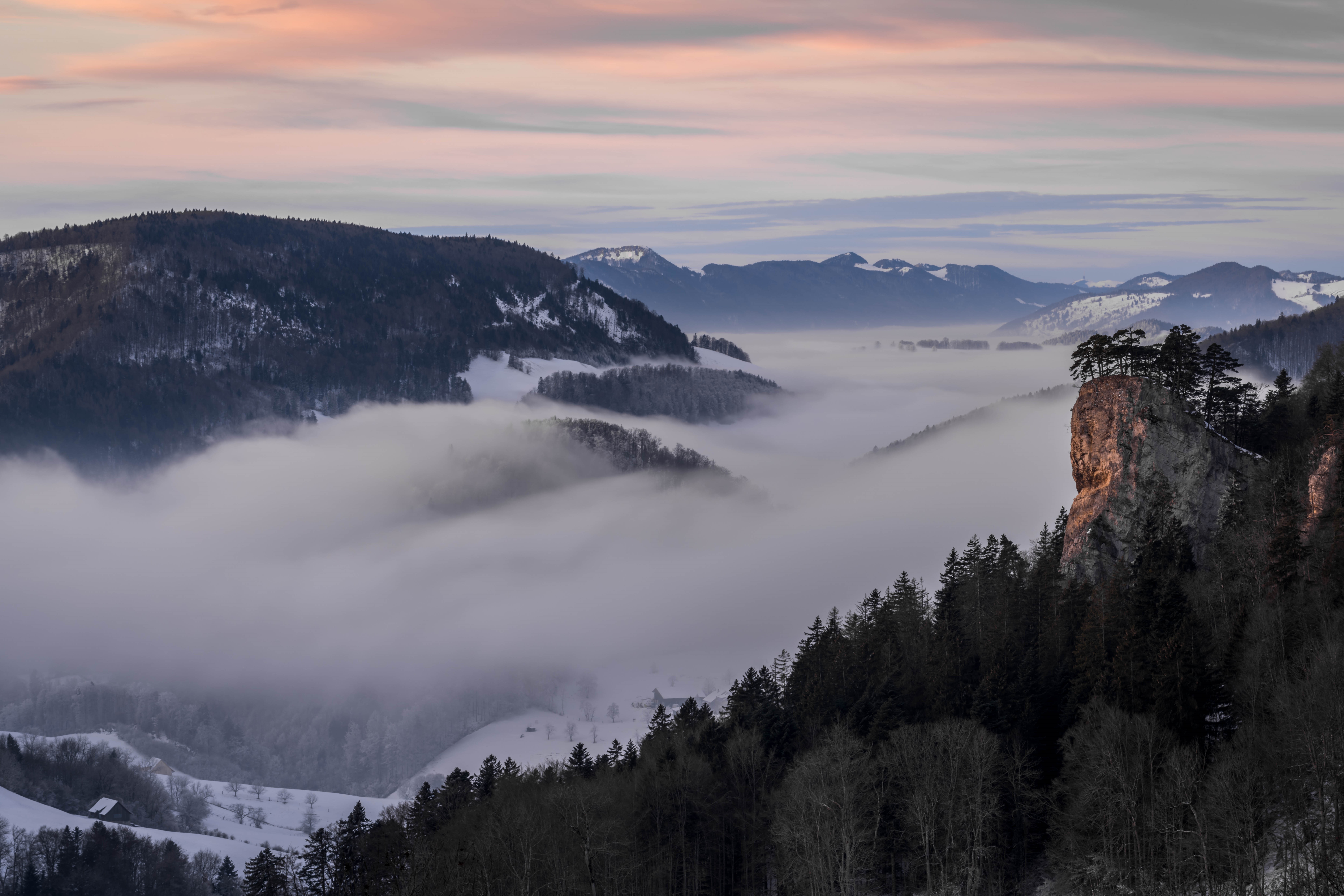 Foggy Valley with Snow-Covered Mountains and Rocky Outcrop HD Wallpaper