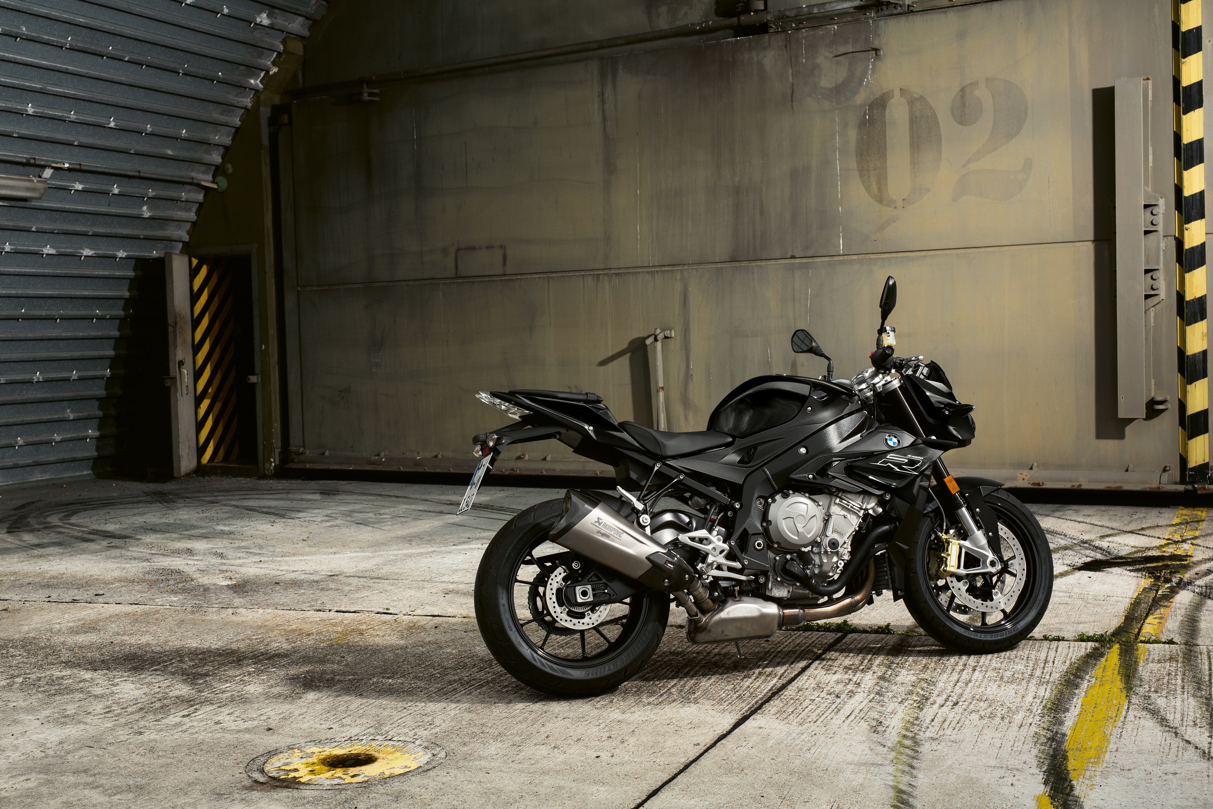 Black BMW S1000R motorcycle in industrial setting HD Wallpaper