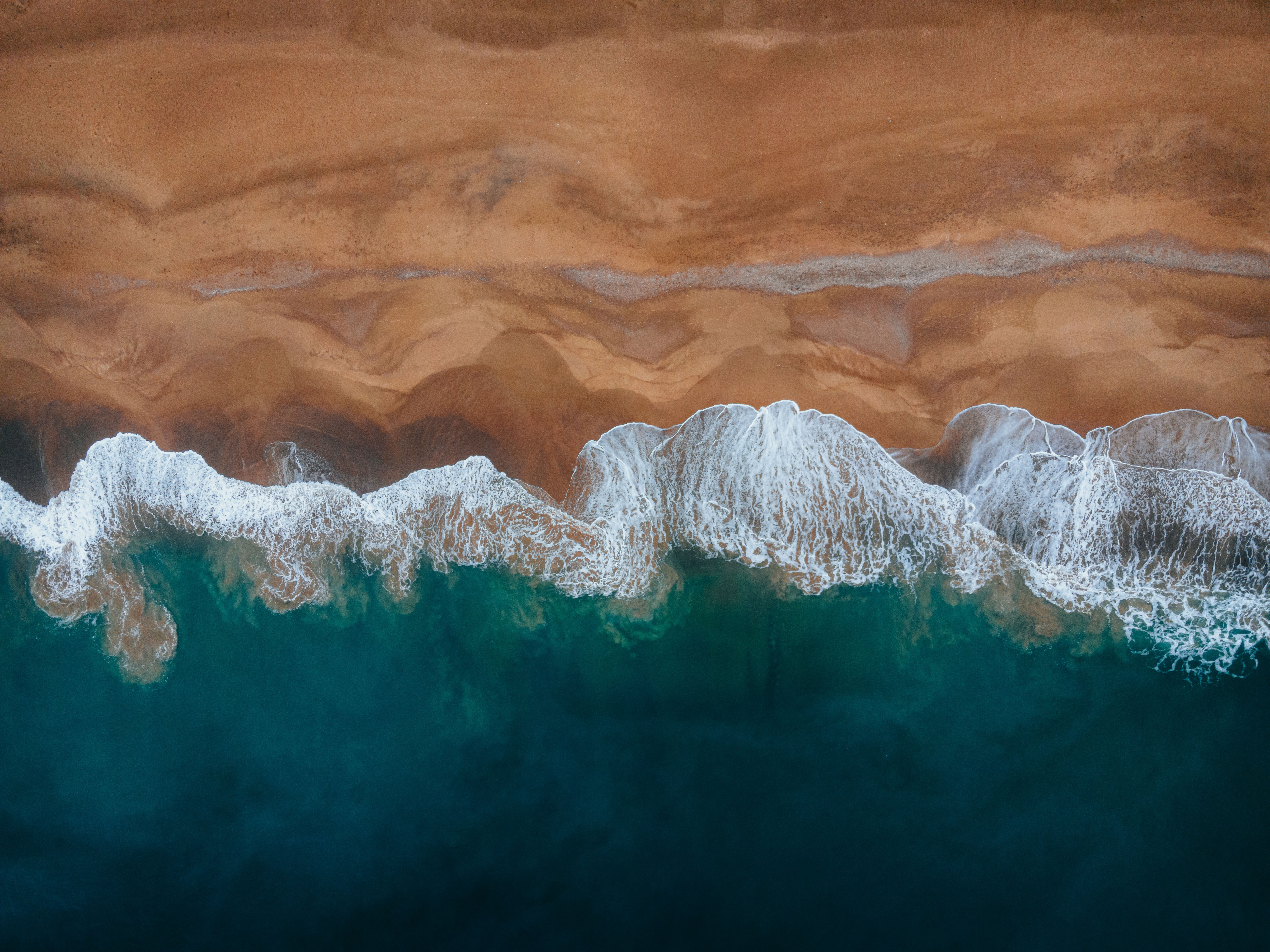 Aerial view of a sandy beach and ocean waves HD Wallpaper