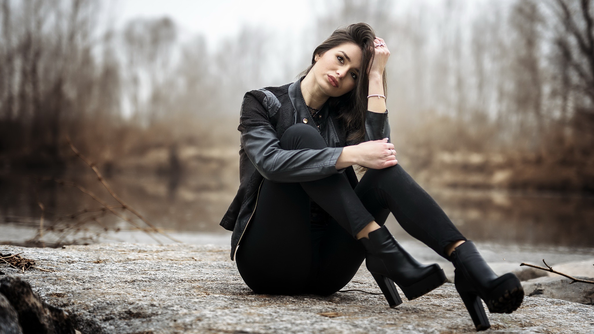 Woman in black jacket and pants sitting on rocks HD Wallpaper