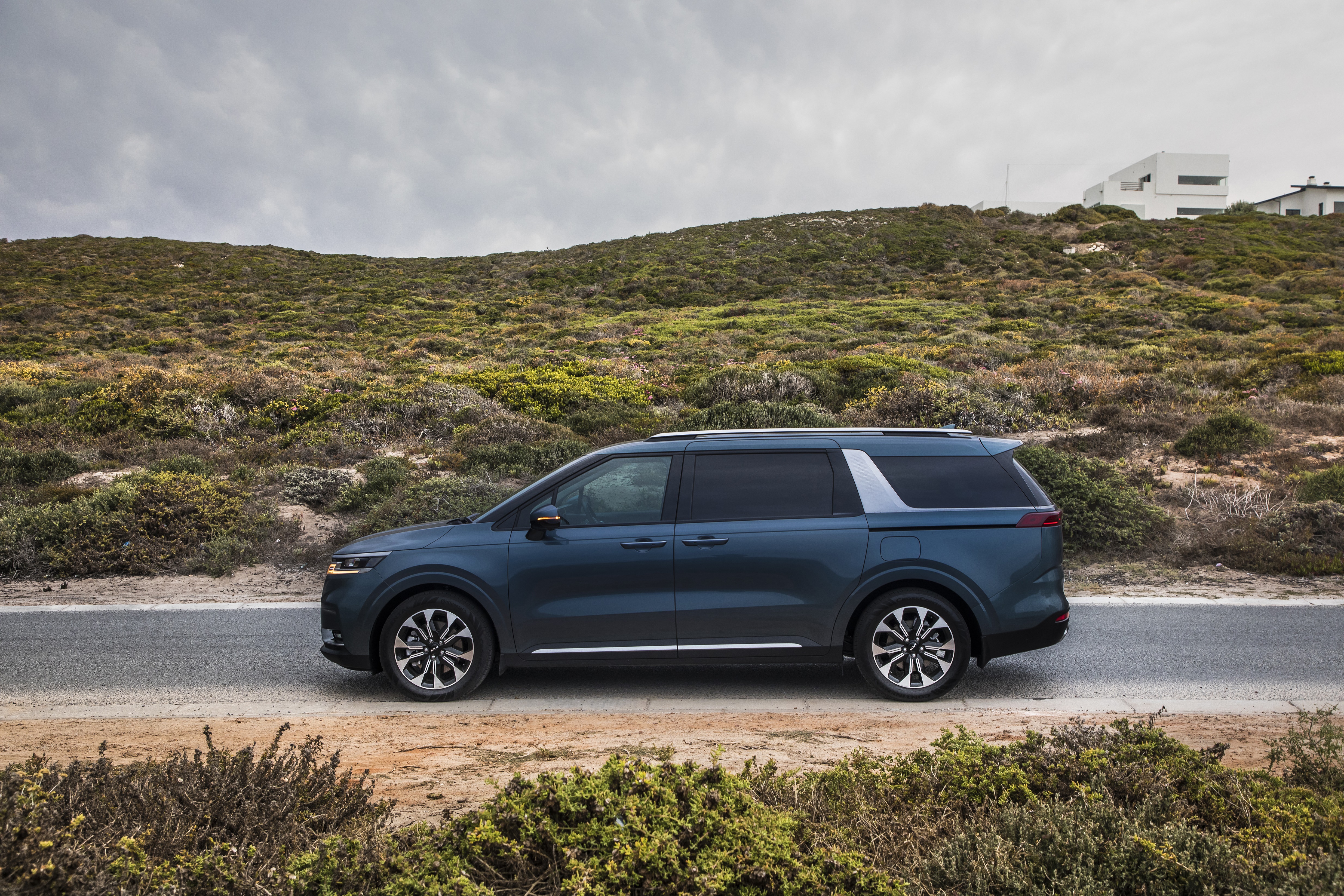 Blue Kia Carnival parked on a coastal road HD Wallpaper
