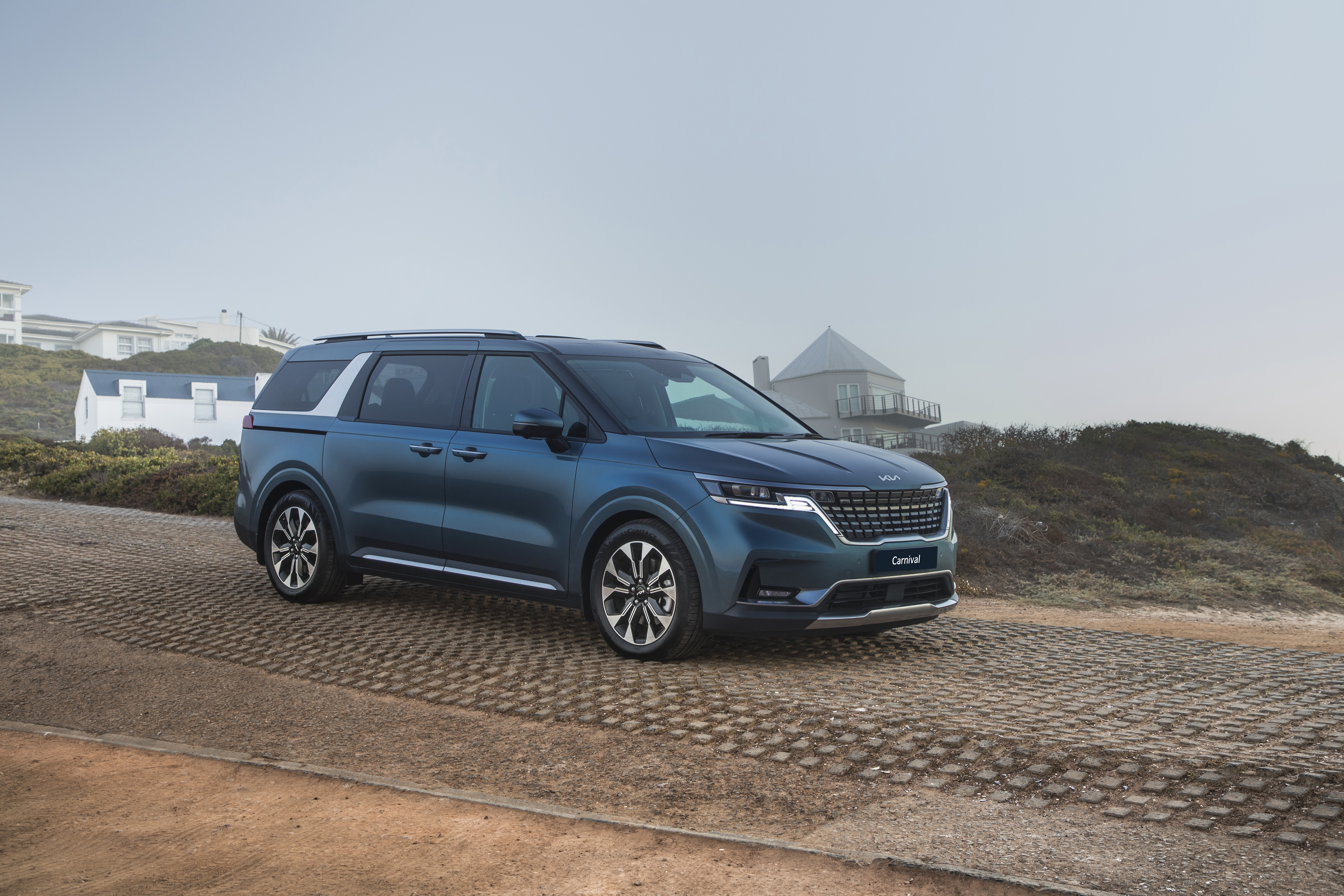 Blue Kia Carnival parked on a coastal road HD Wallpaper