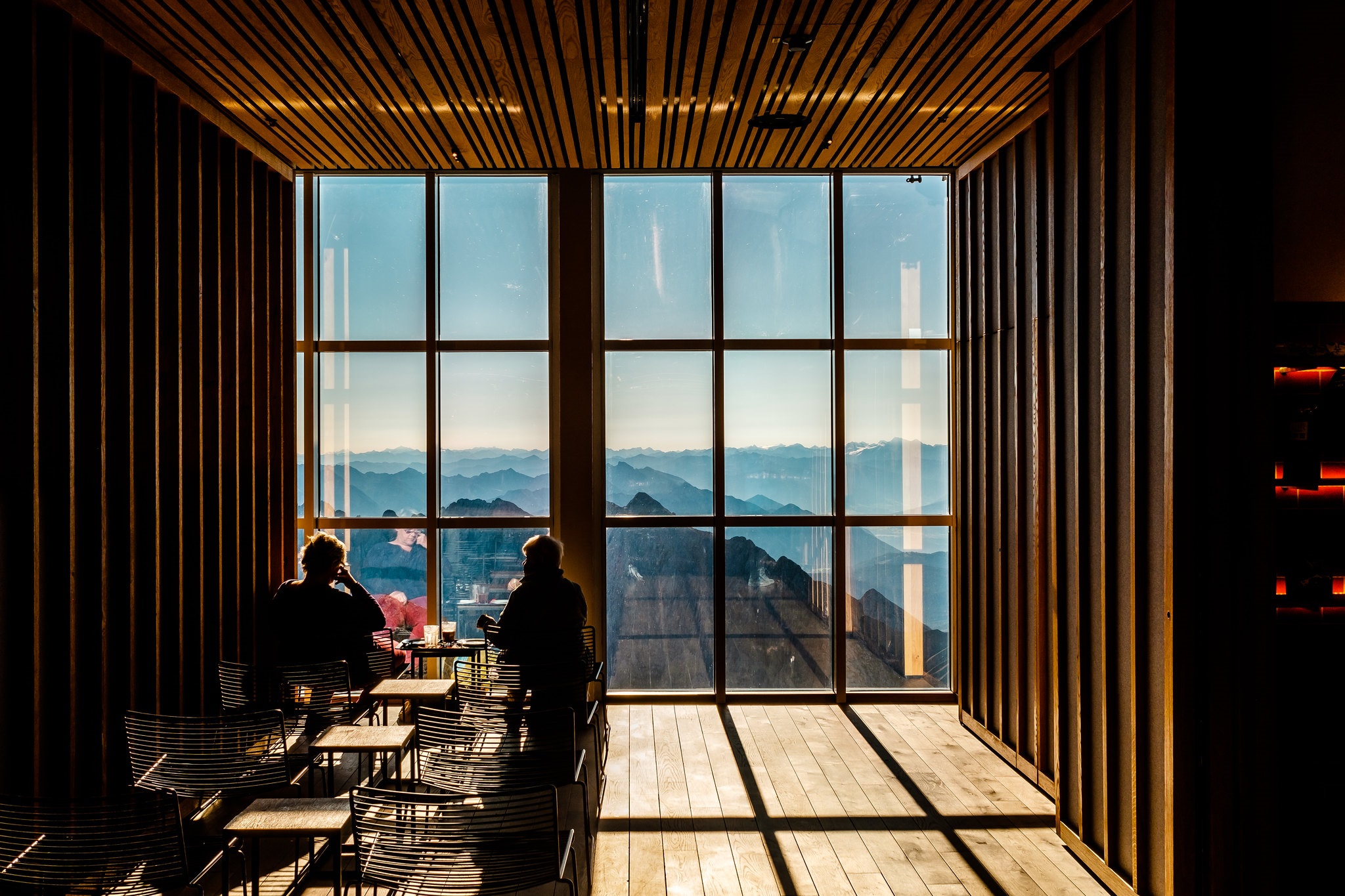 People in a room with a view of mountains HD Wallpaper
