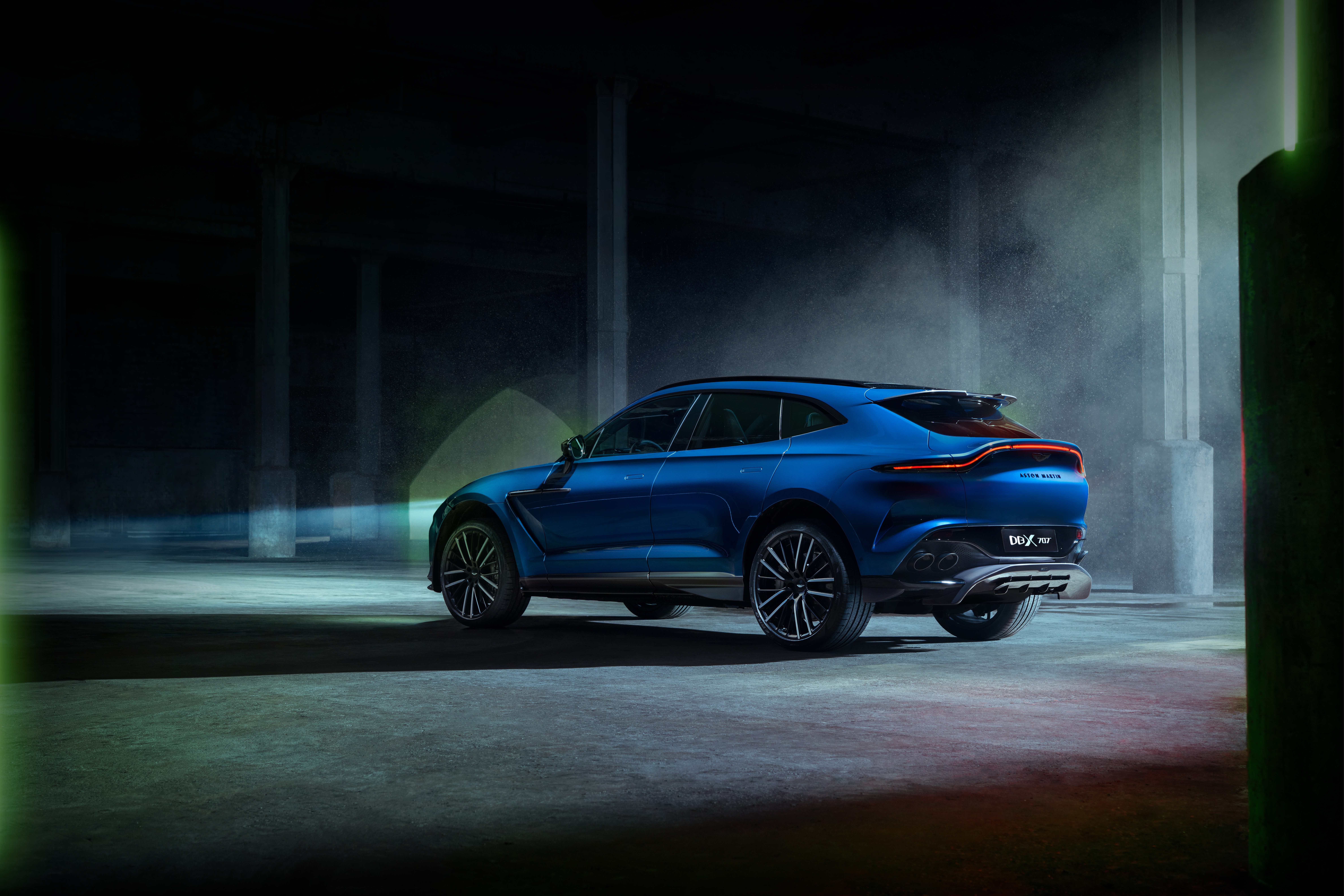 Aston Martin DBX707 SUV in a dark industrial setting HD Wallpaper