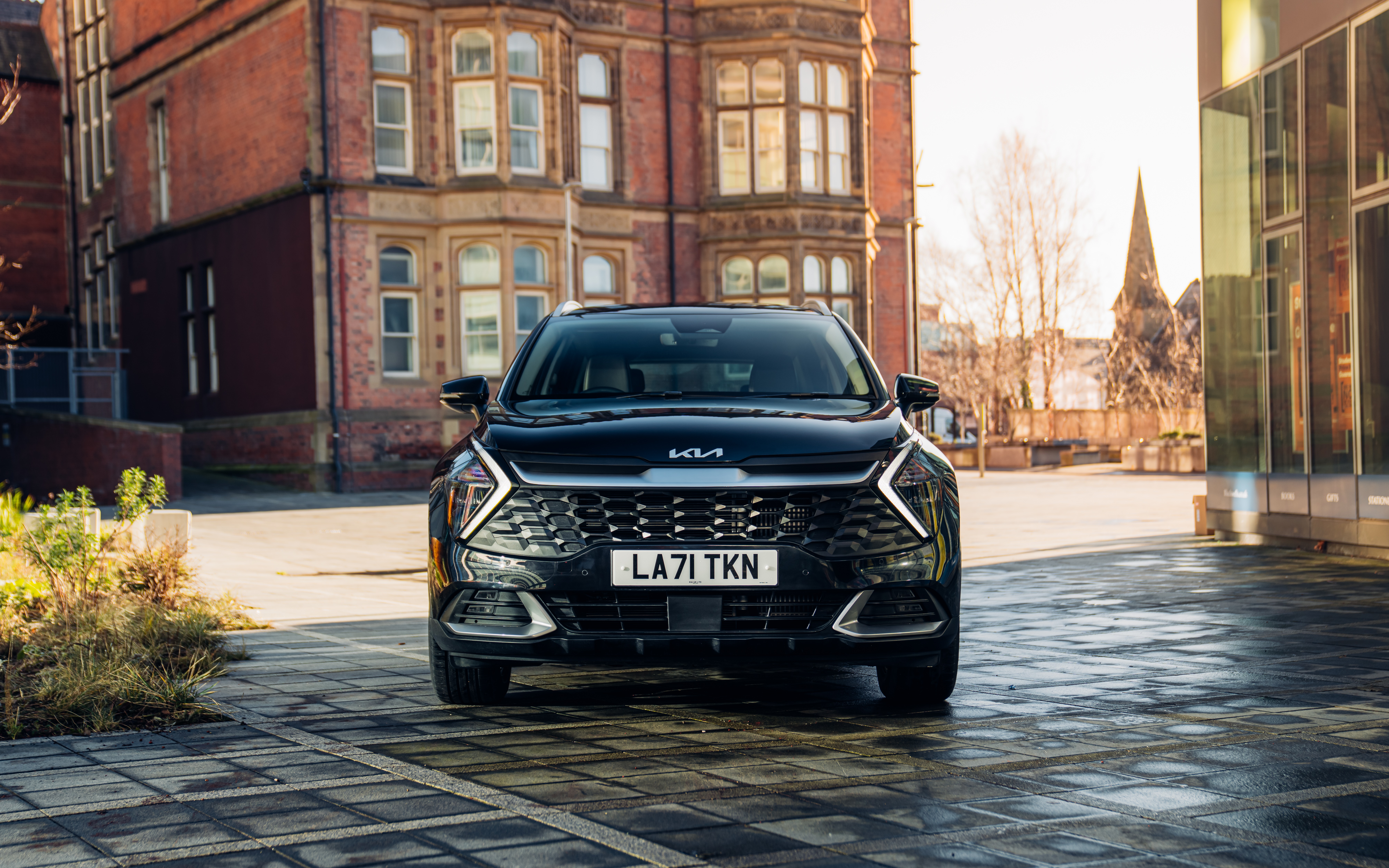 Black Kia Sportage SUV parked in front of a brick building HD Wallpaper