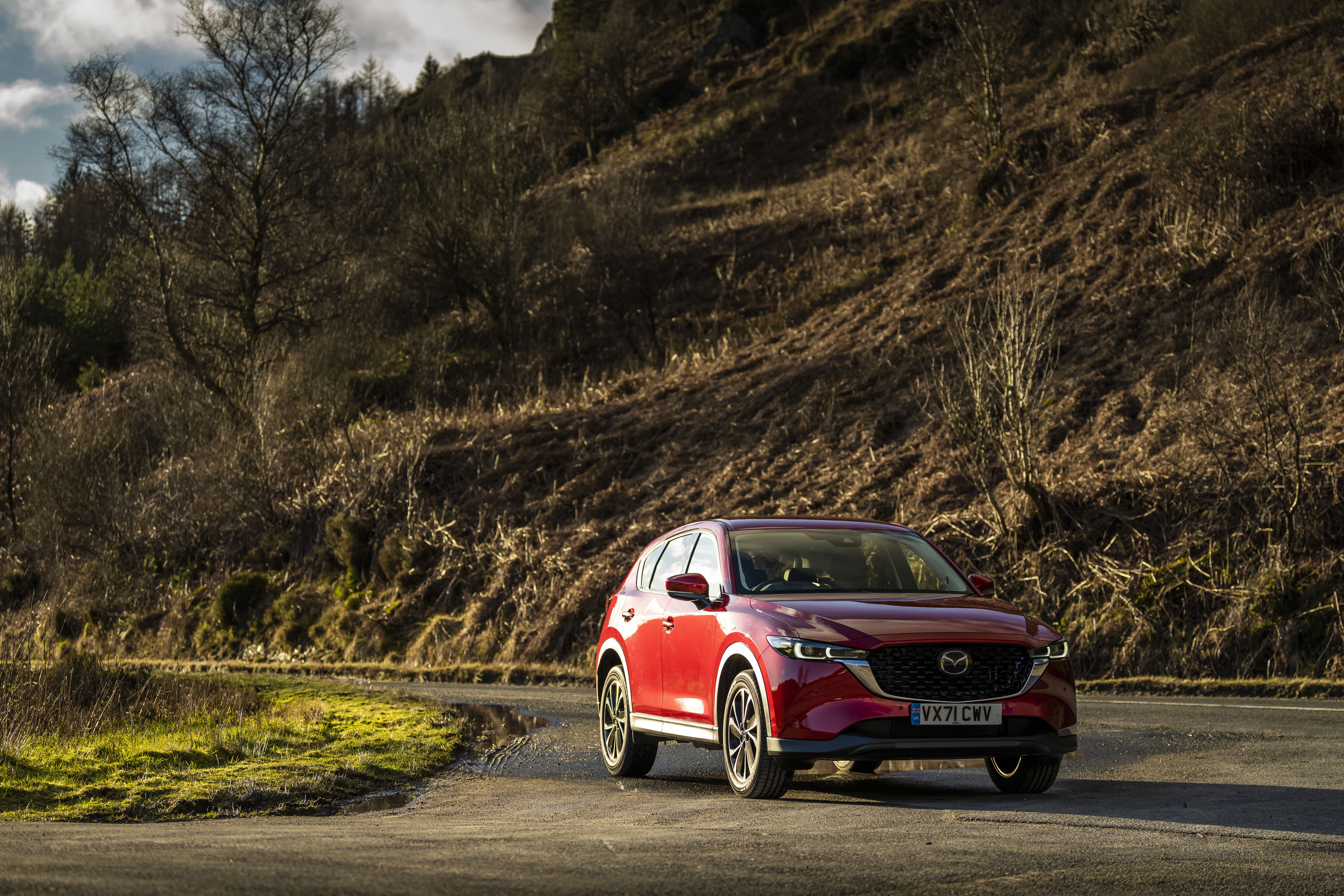 Red Mazda CX-5 SUV on a winding road in a hilly landscape HD Wallpaper