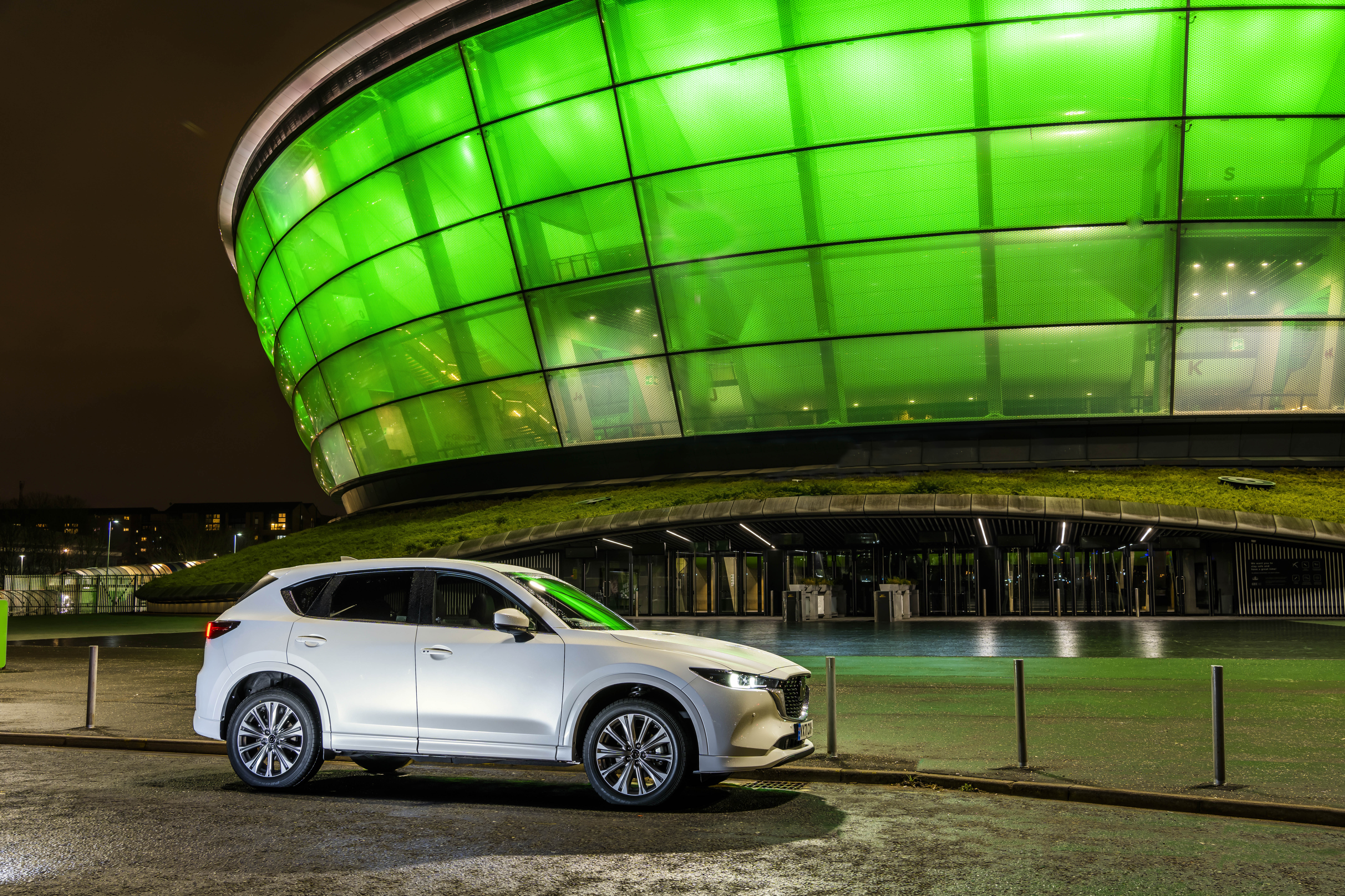 White Mazda CX-5 parked in front of a green illuminated building HD Wallpaper