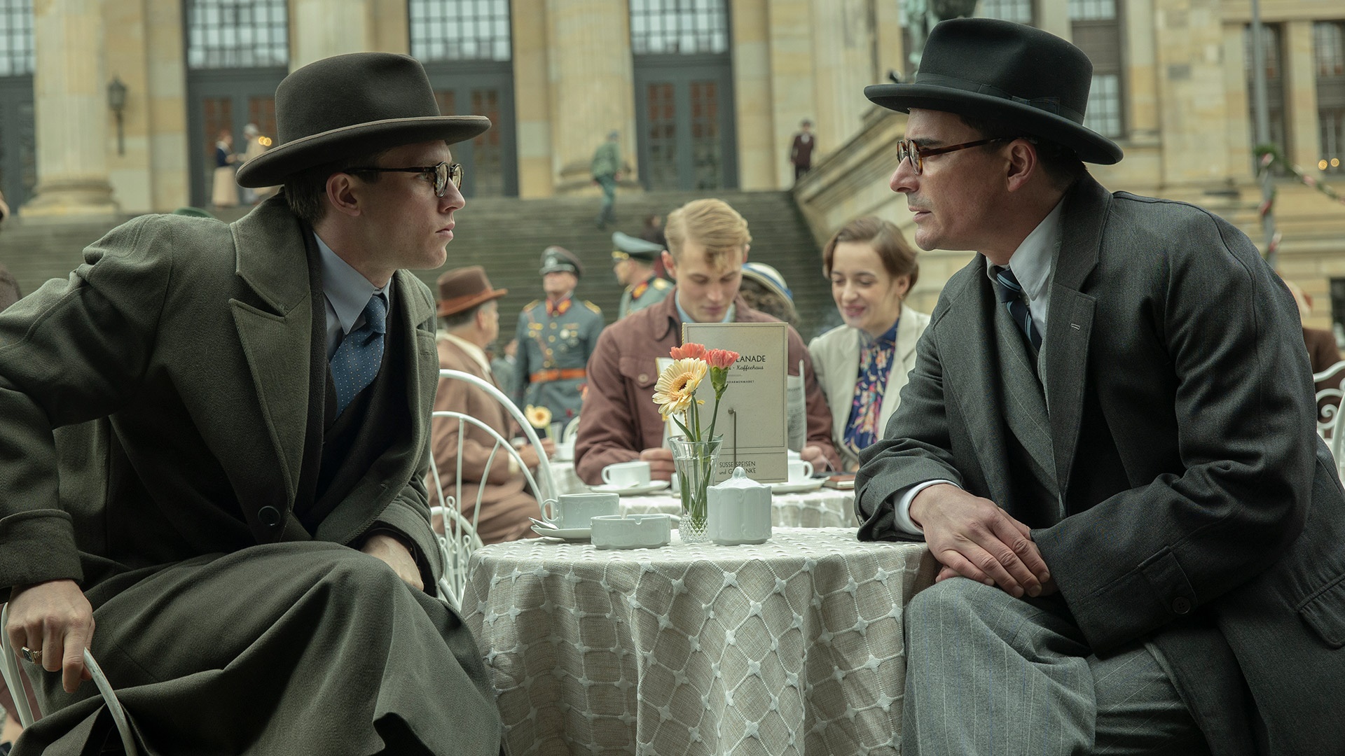 Two men in hats and suits at a cafe in Munich HD Wallpaper