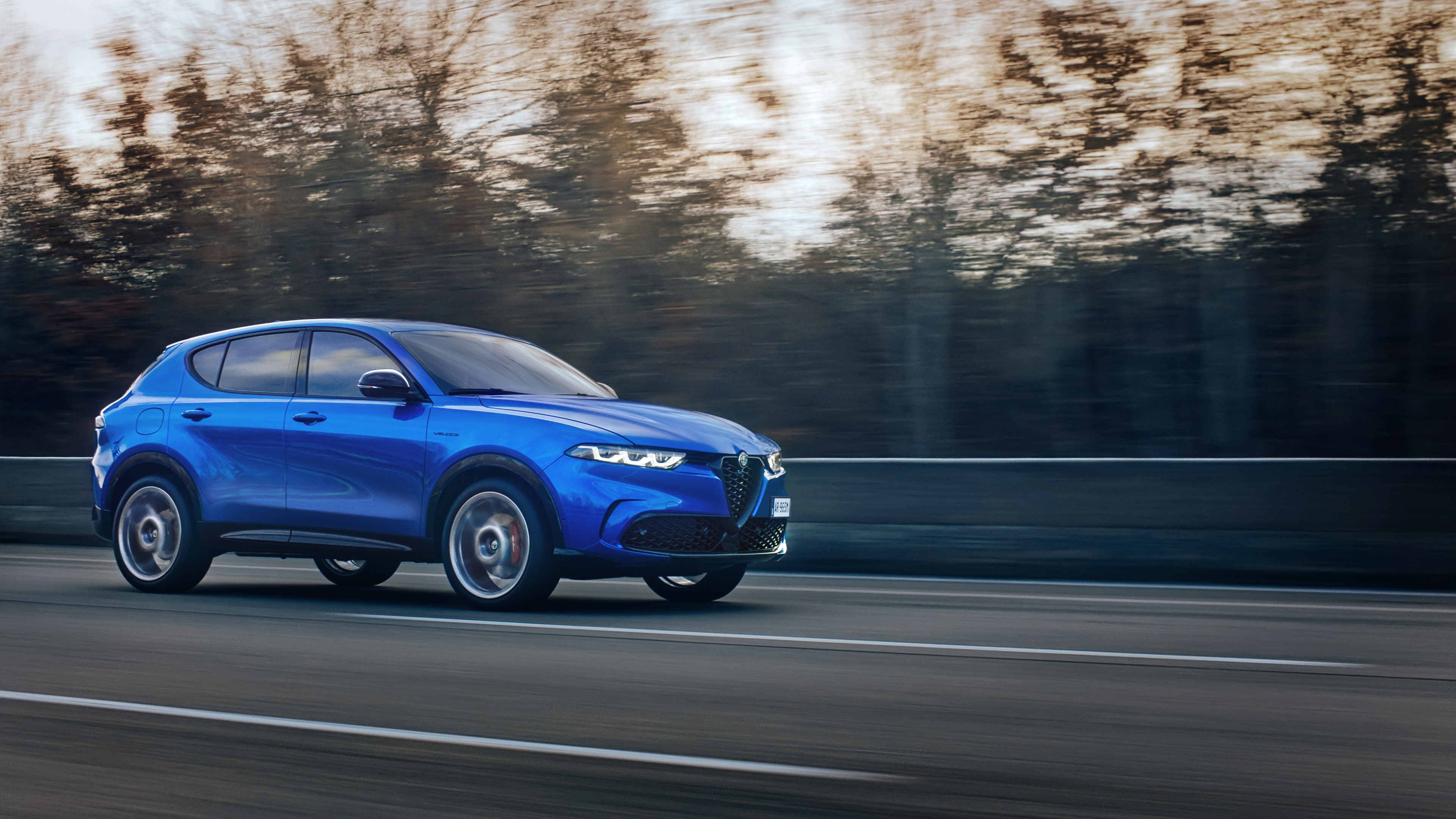 Blue Alfa Romeo Tonale Veloce driving on a highway HD Wallpaper