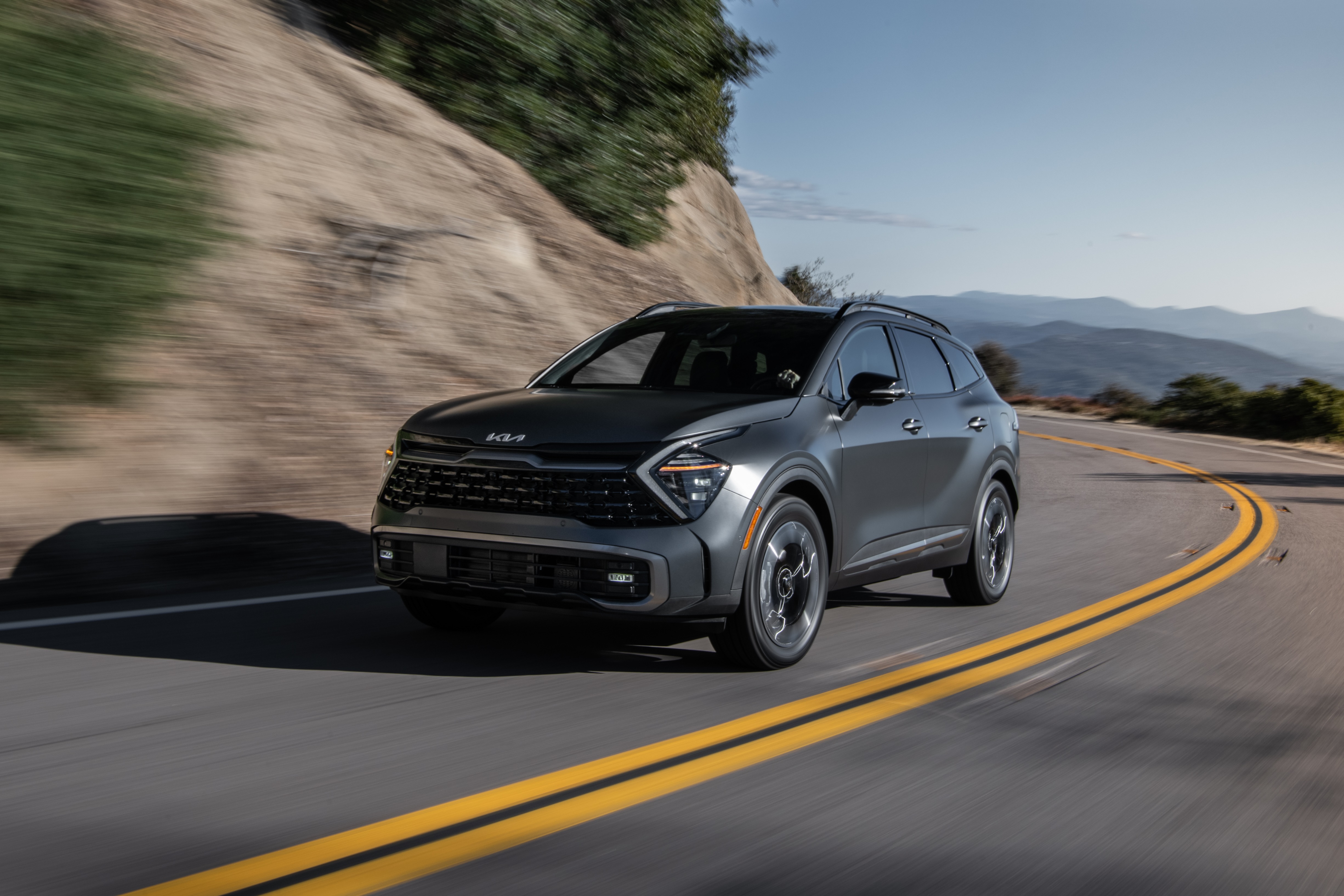 Kia Sportage PHEV X-Line SUV driving on a winding road HD Wallpaper