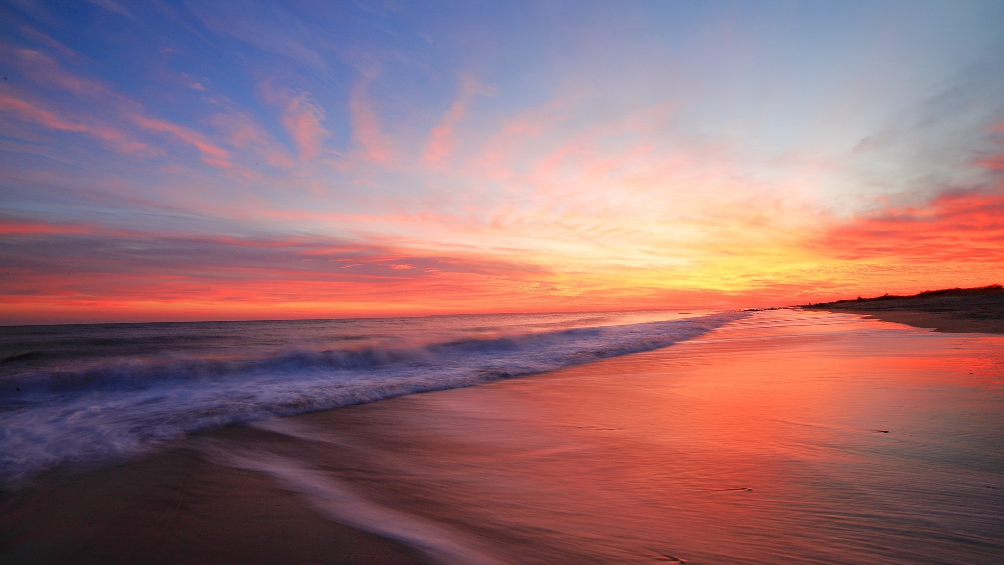 Sunset over a beach with colorful clouds and ocean waves HD Wallpaper