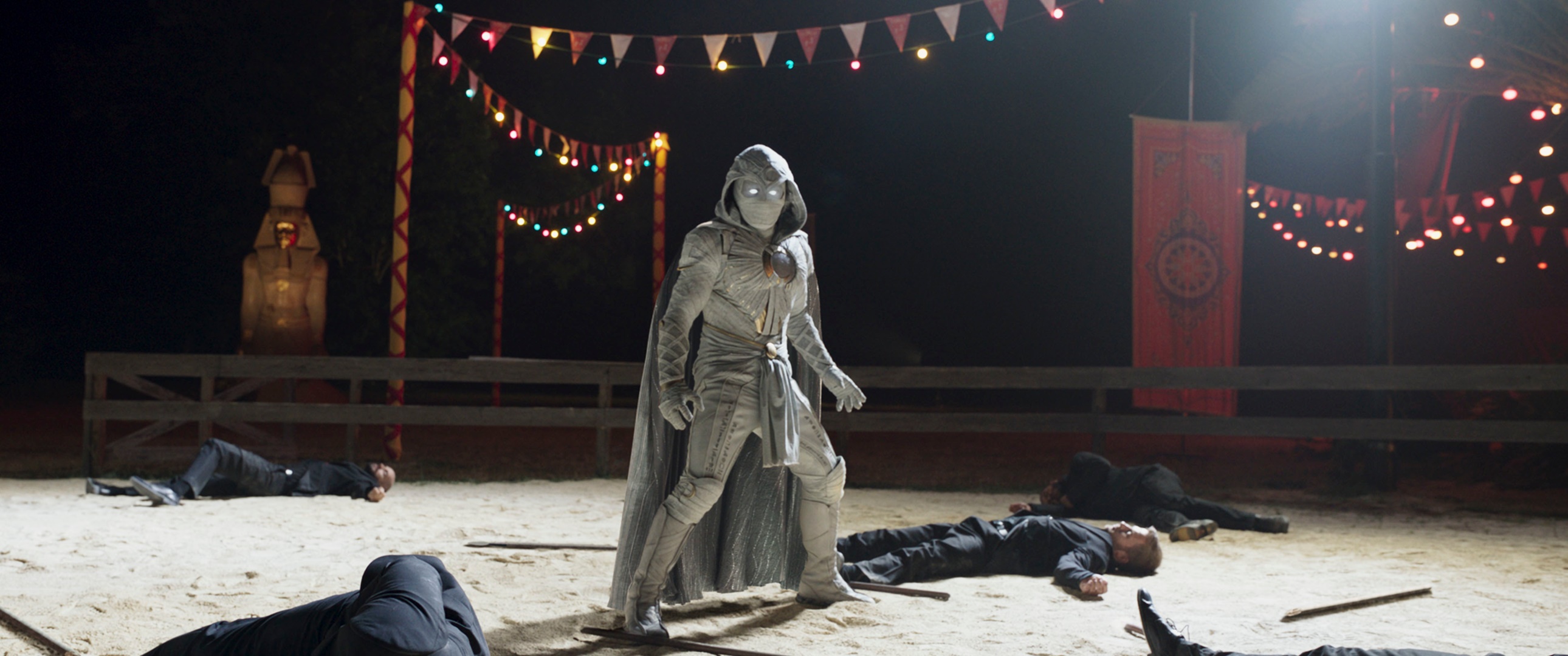 Moon Knight standing in a sandy arena with defeated opponents HD Wallpaper