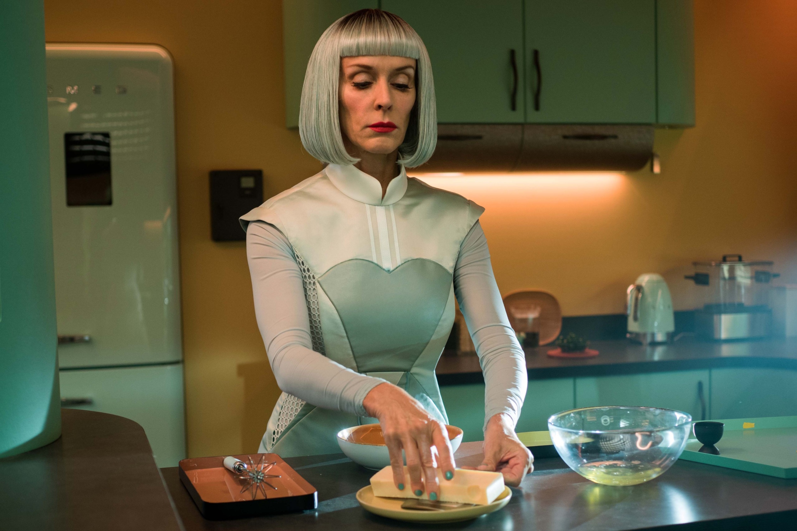 Woman in futuristic outfit preparing food in a retro kitchen HD Wallpaper