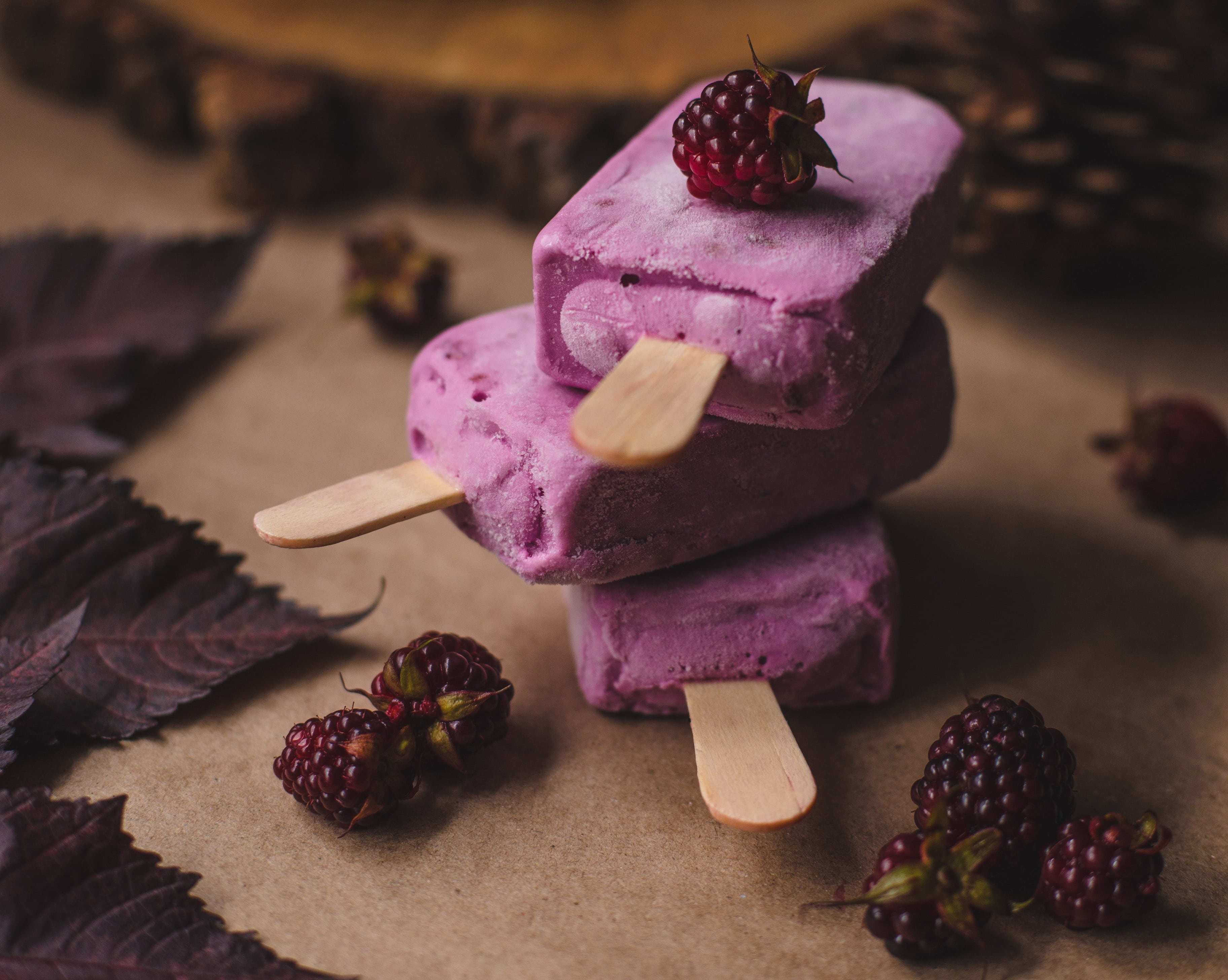 Stack of purple berry popsicles with fresh berries and leaves HD Wallpaper