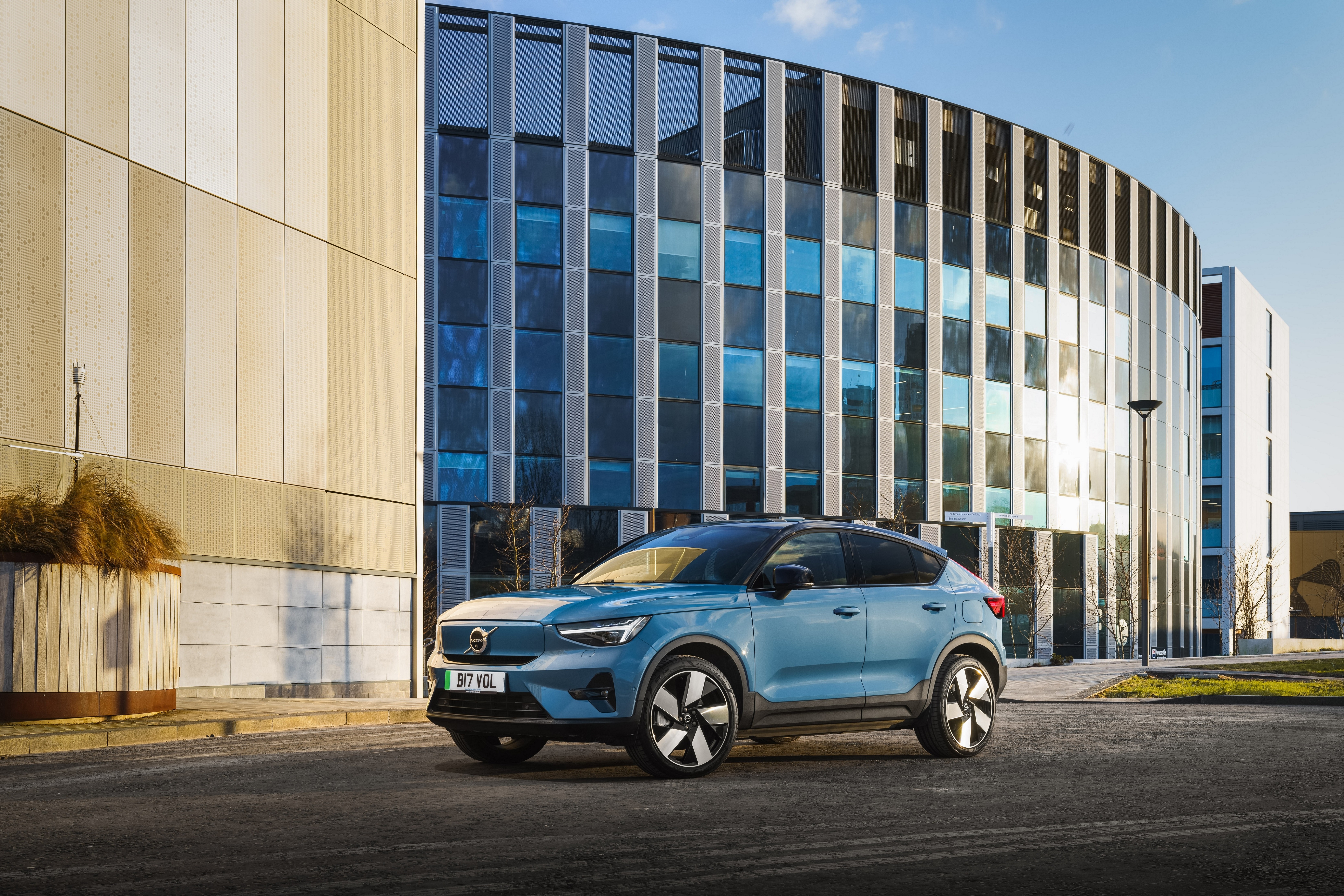 Blue Volvo C40 Recharge SUV parked outside modern building HD Wallpaper