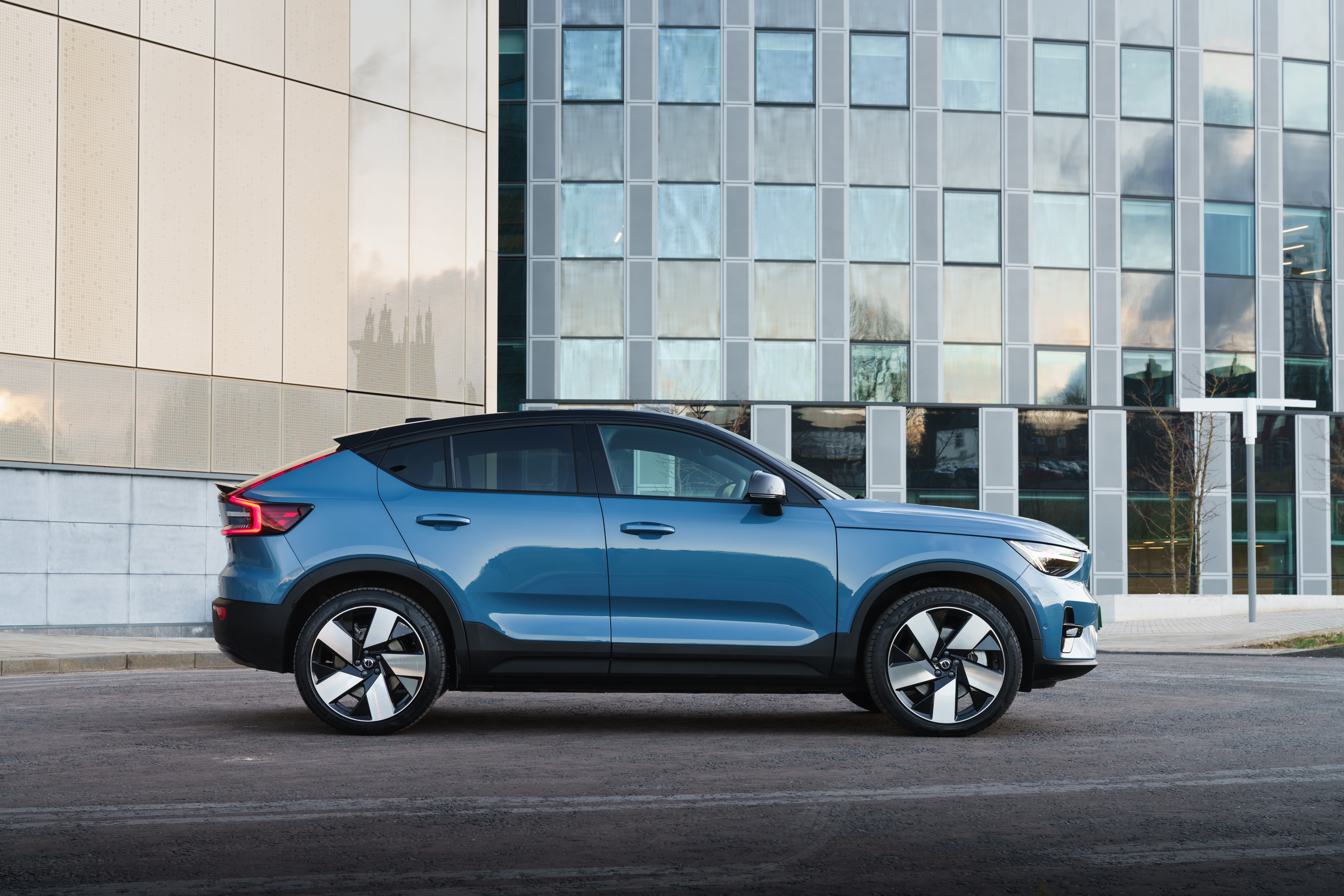 Blue Volvo C40 Recharge parked in front of a modern building HD Wallpaper