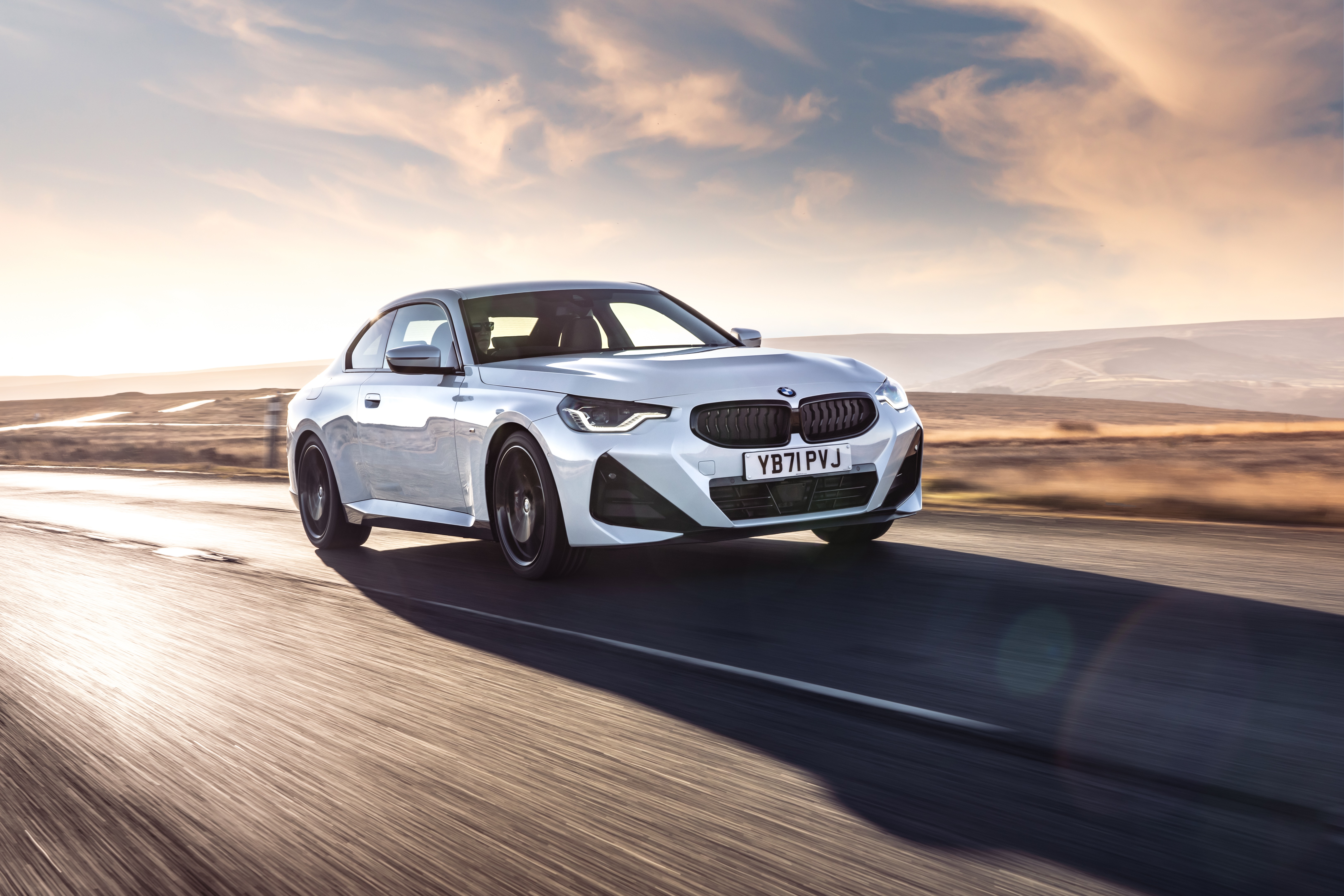 White BMW 220i Coupé M Sport driving on a road HD Wallpaper