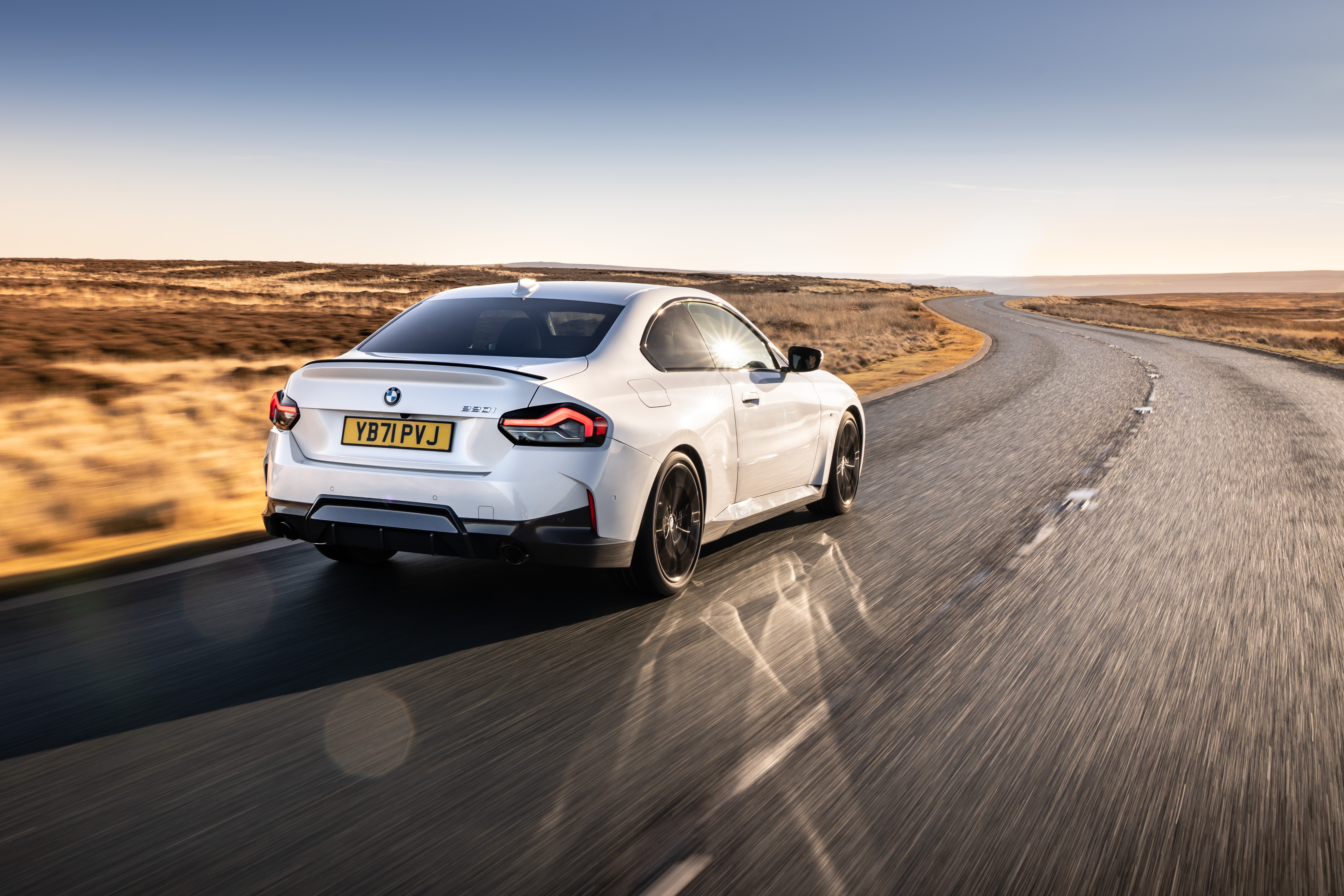 White BMW 220i Coupé M Sport driving on a road HD Wallpaper