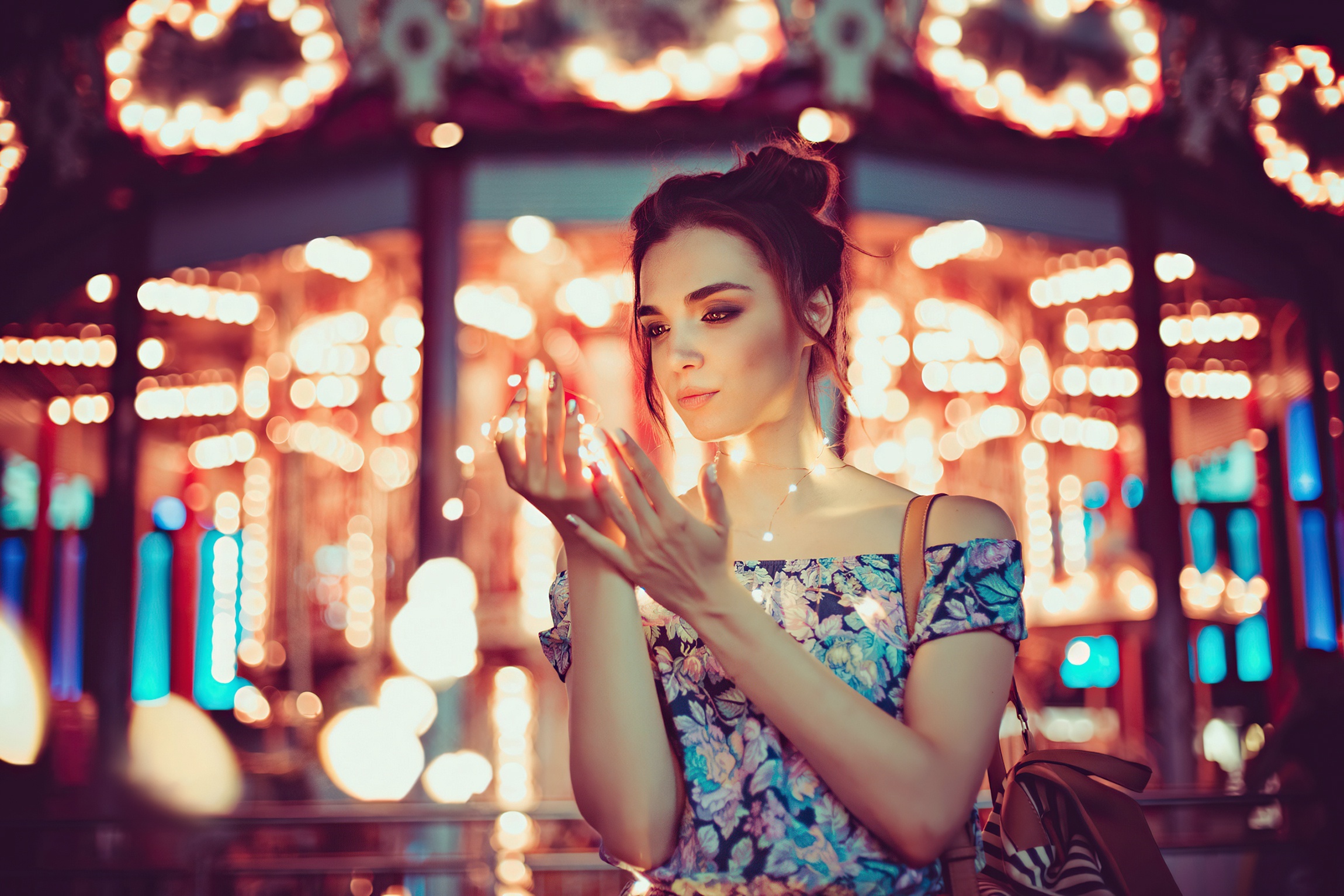 Woman holding fairy lights with carousel lights in background HD Wallpaper
