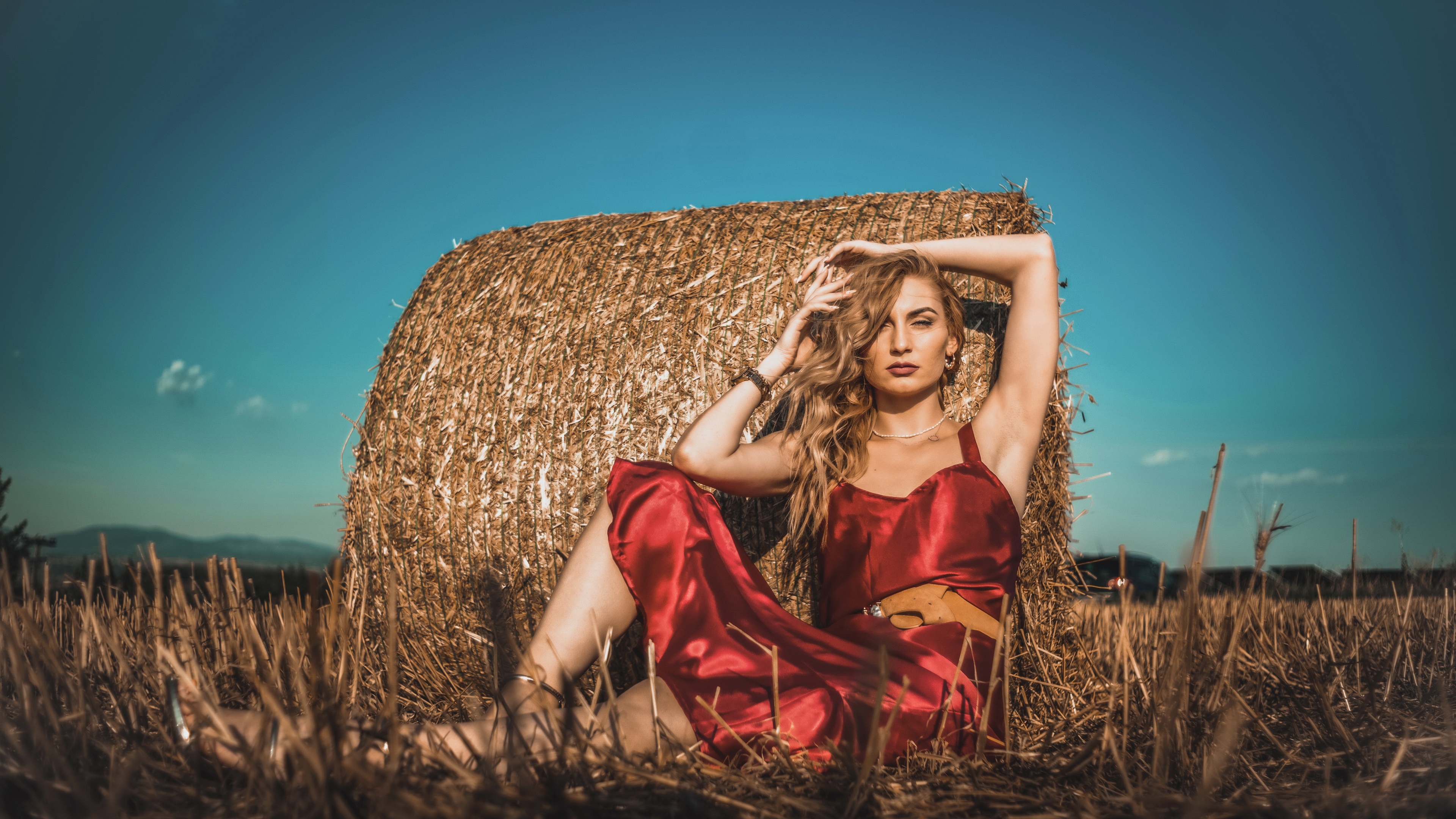 Woman in red dress sitting by hay bale HD Wallpaper