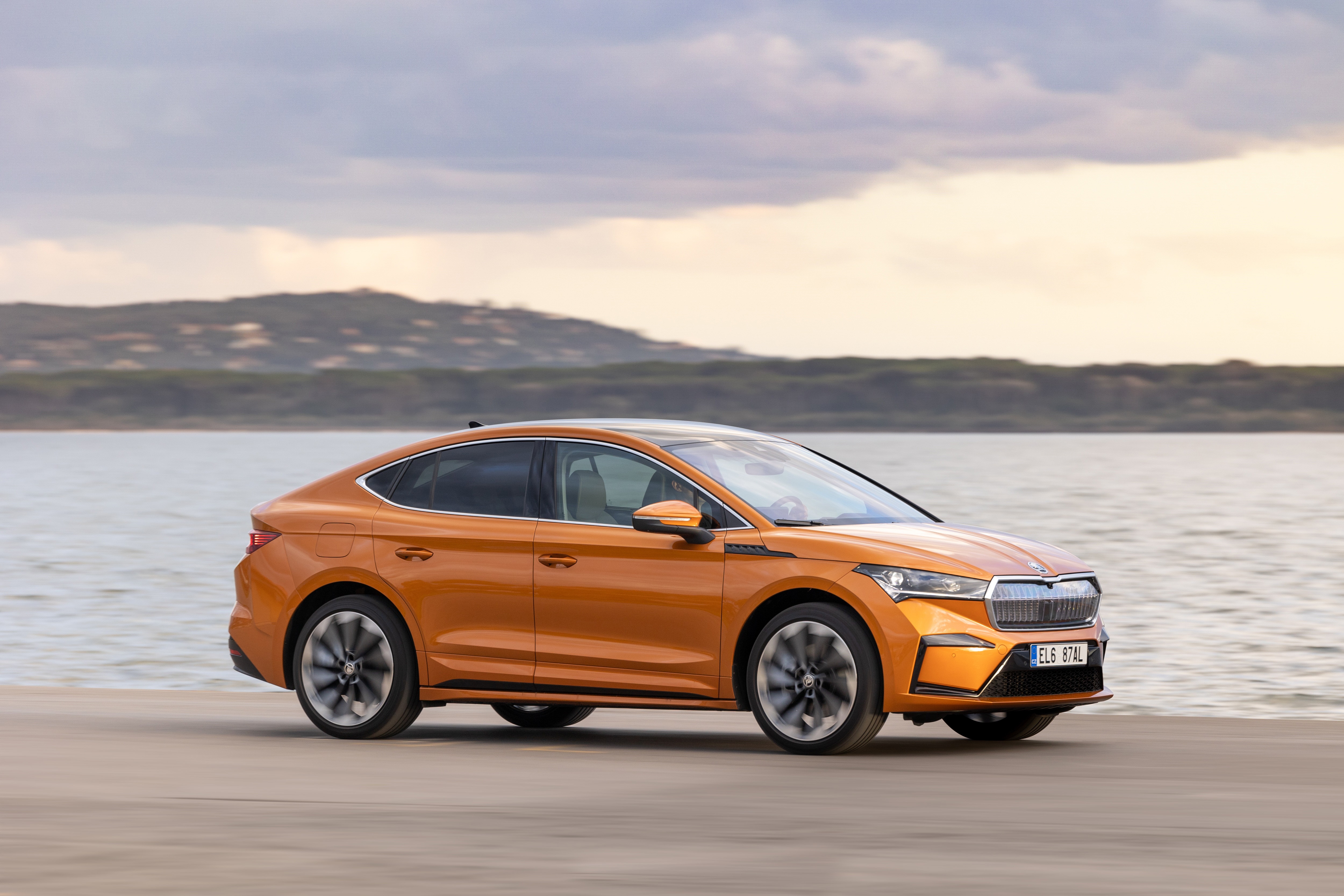 Orange Škoda Enyaq iV 80 electric car driving by water HD Wallpaper