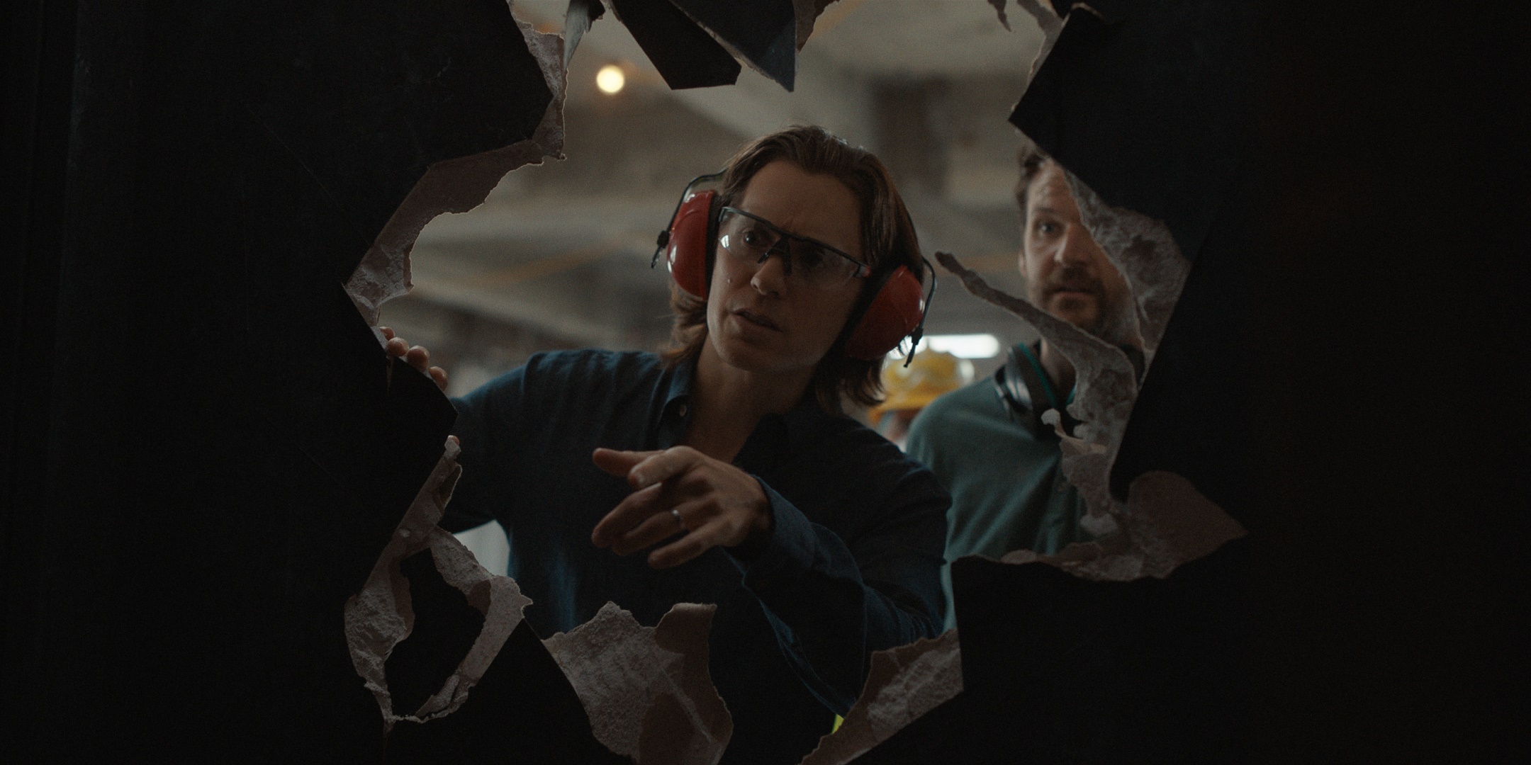 Adam Neumann and partner looking through hole in wall HD Wallpaper