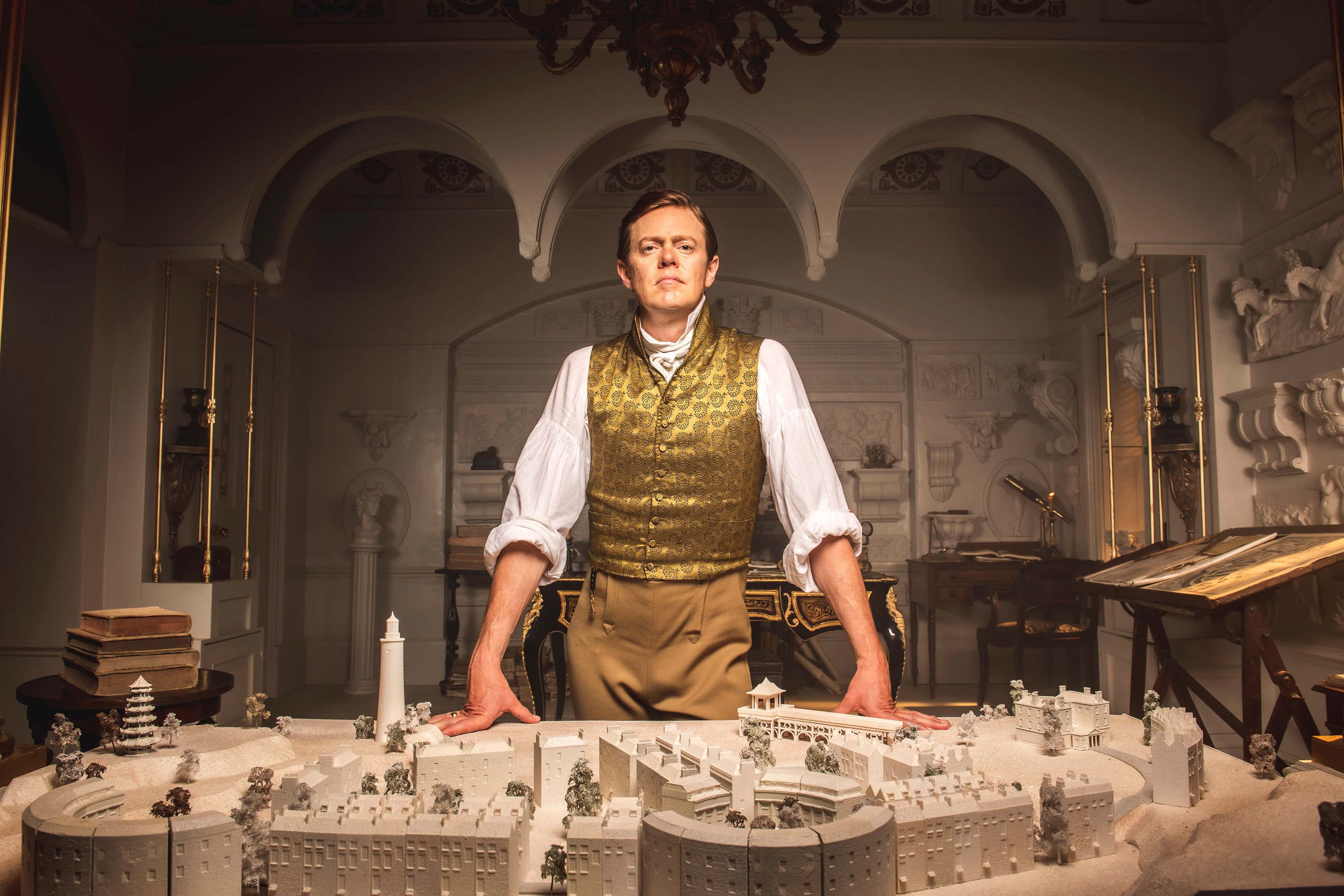 Man in historical attire stands behind architectural model HD Wallpaper
