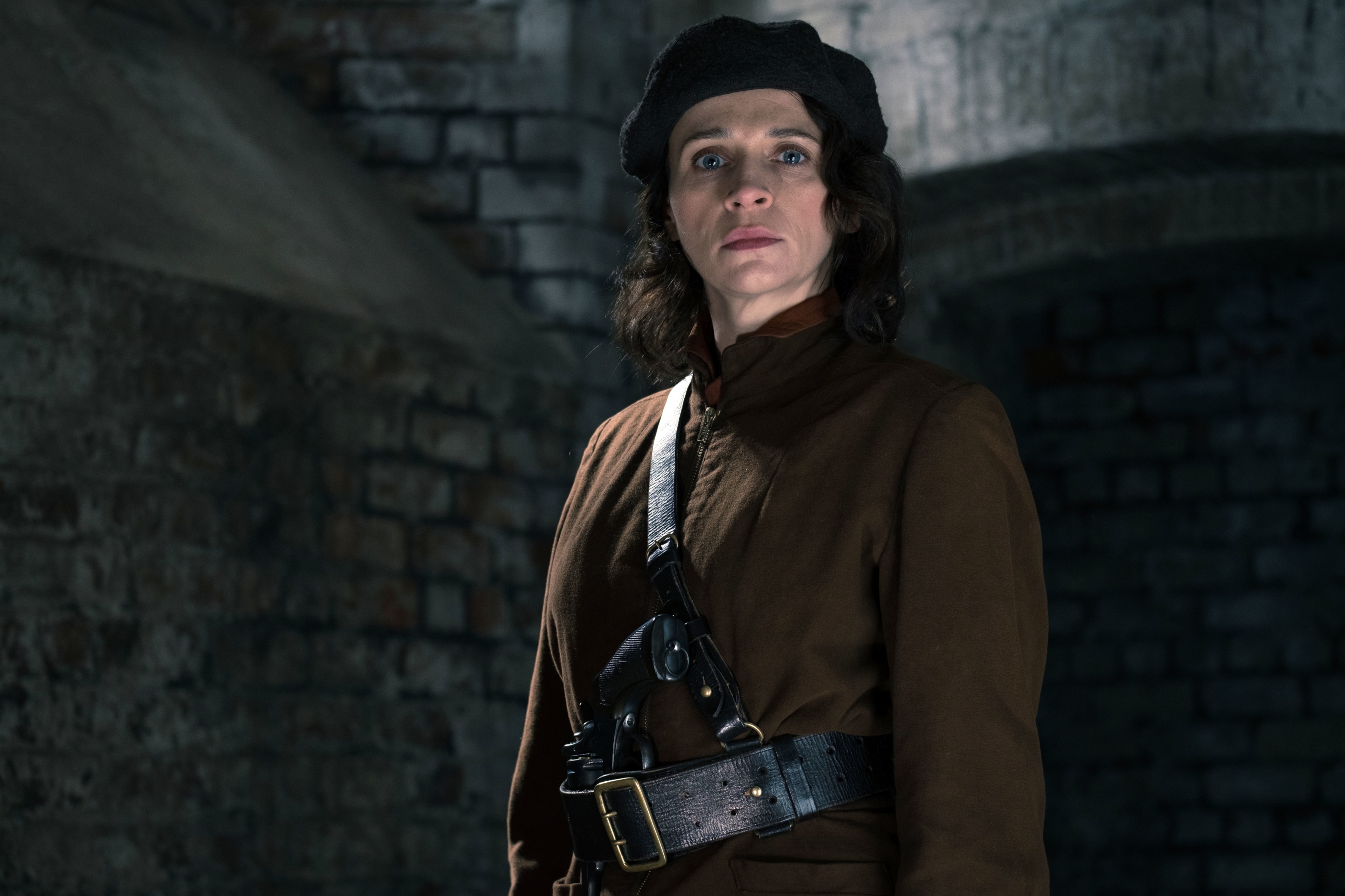 Woman in brown coat and beret with gun holster HD Wallpaper