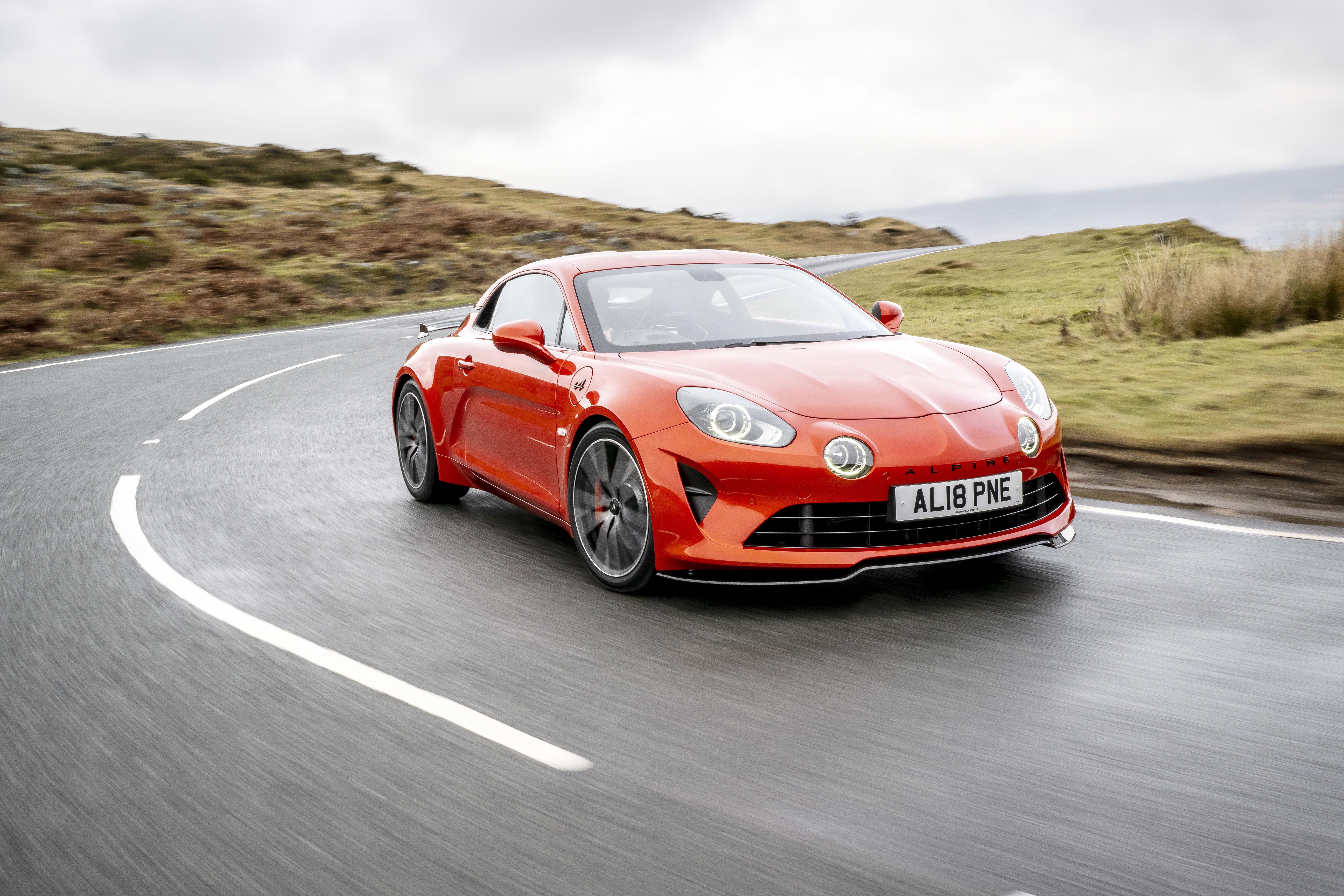 Orange Alpine A110S driving on a winding road HD Wallpaper