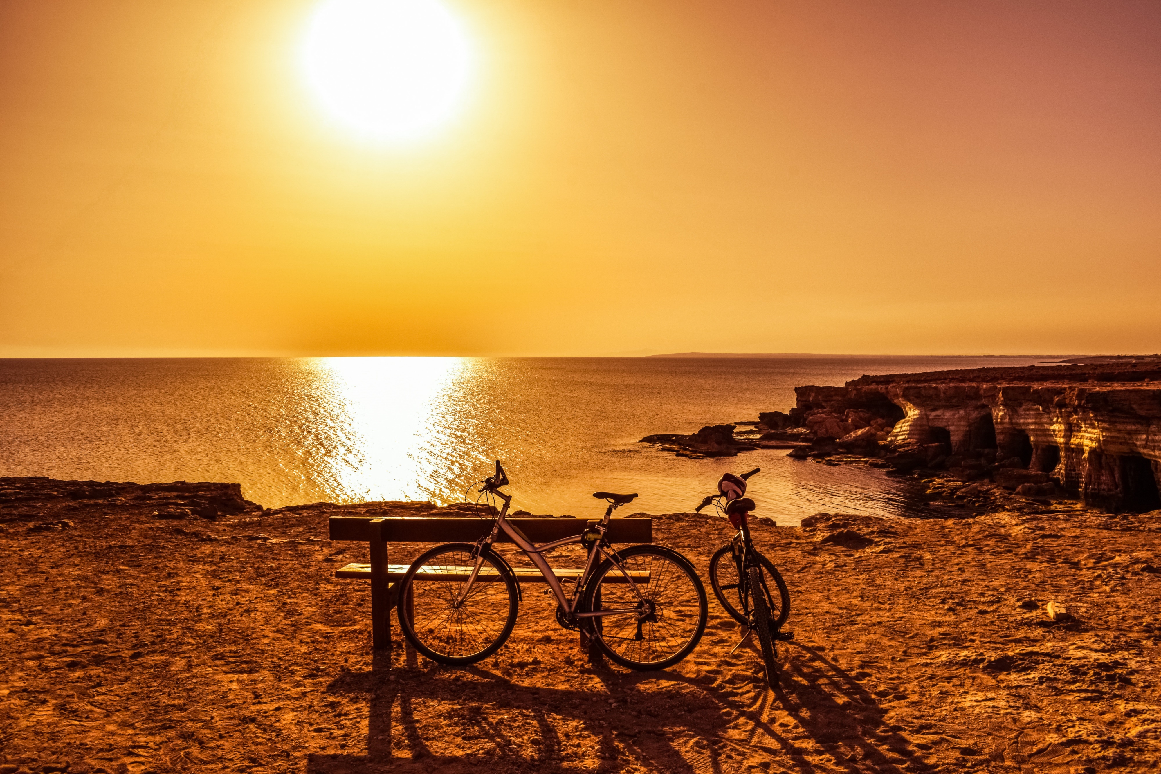 Bicycles and bench at sunset by the sea HD Wallpaper