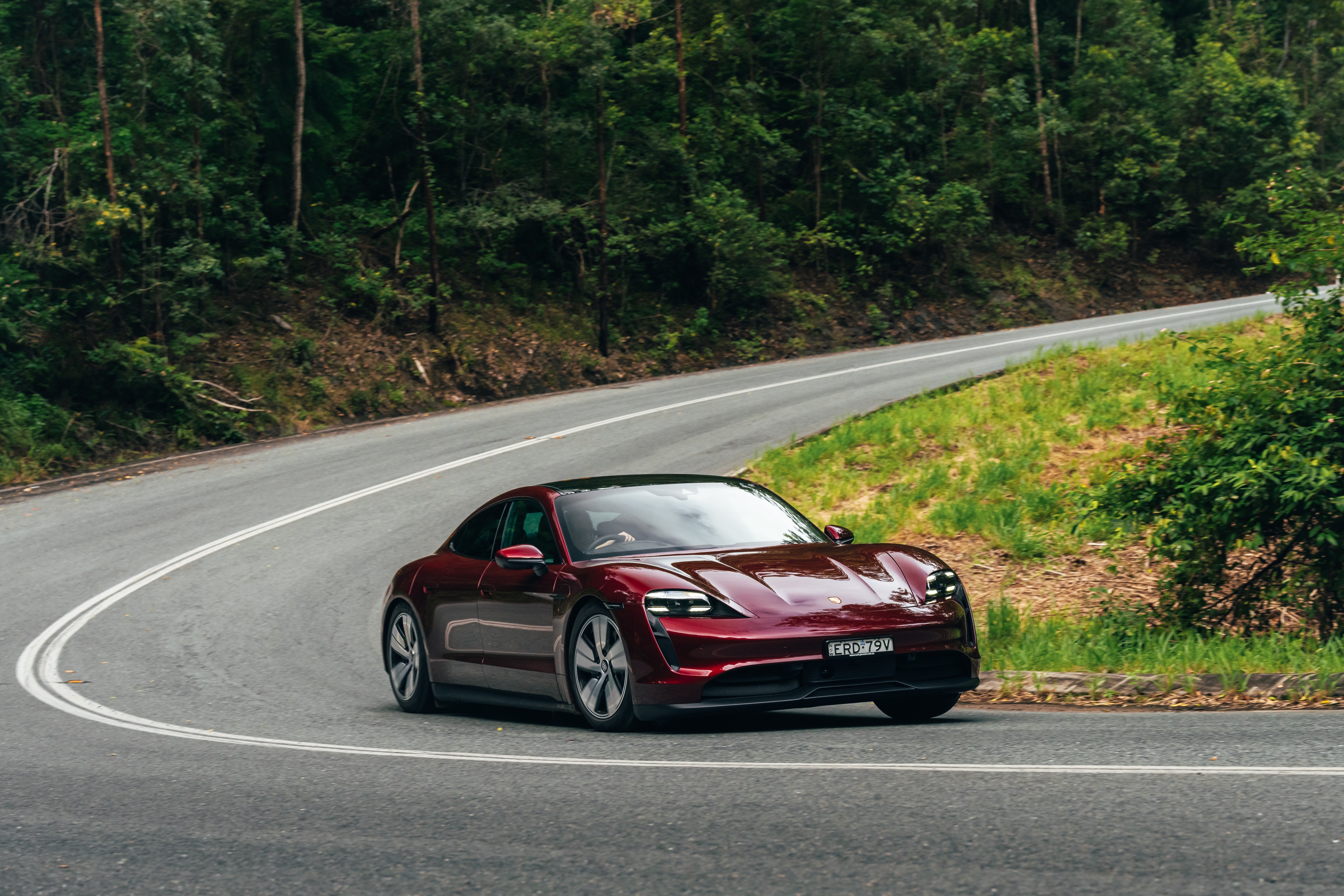 Red Porsche Taycan driving on a winding road HD Wallpaper