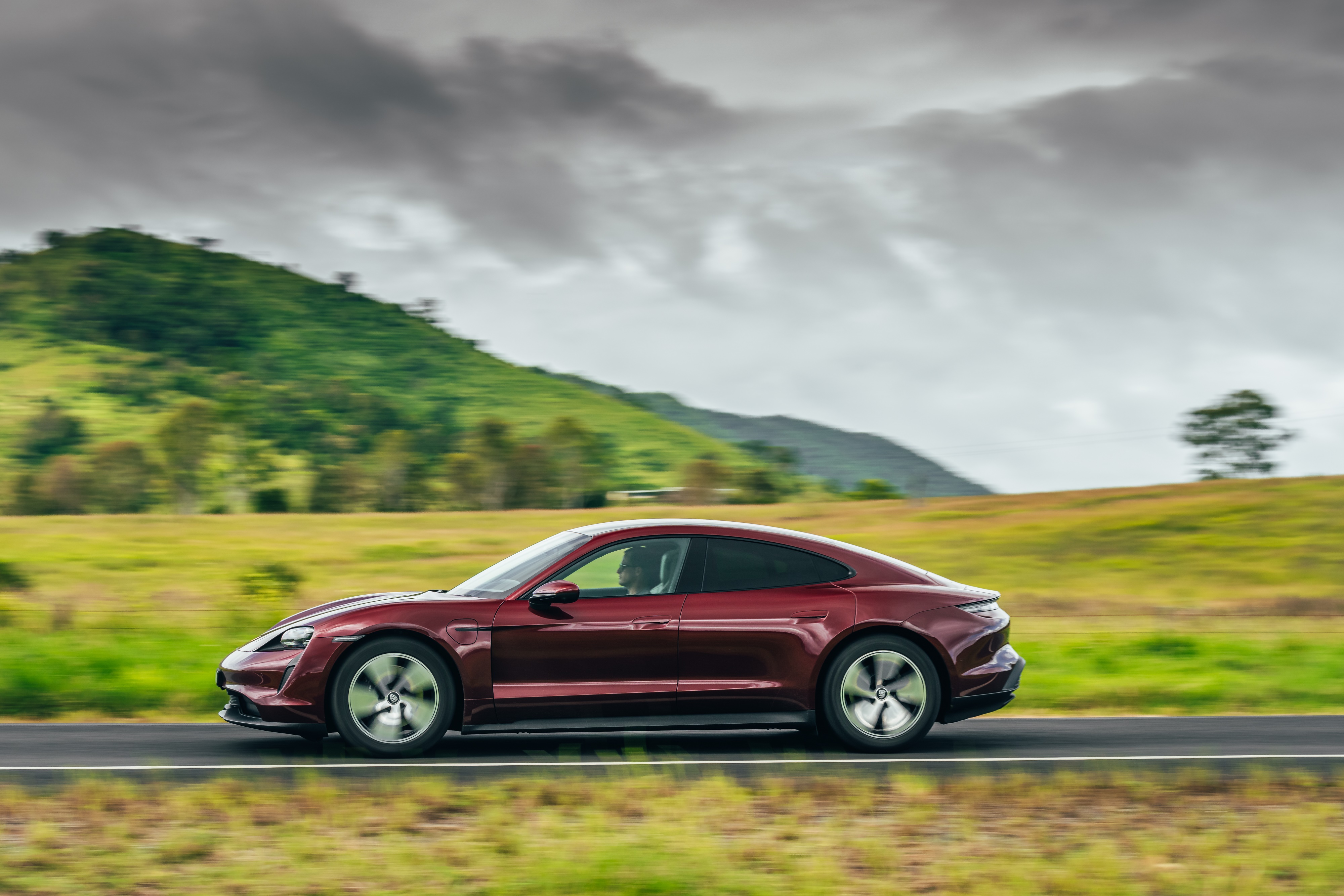 Red Porsche Taycan driving on a road HD Wallpaper