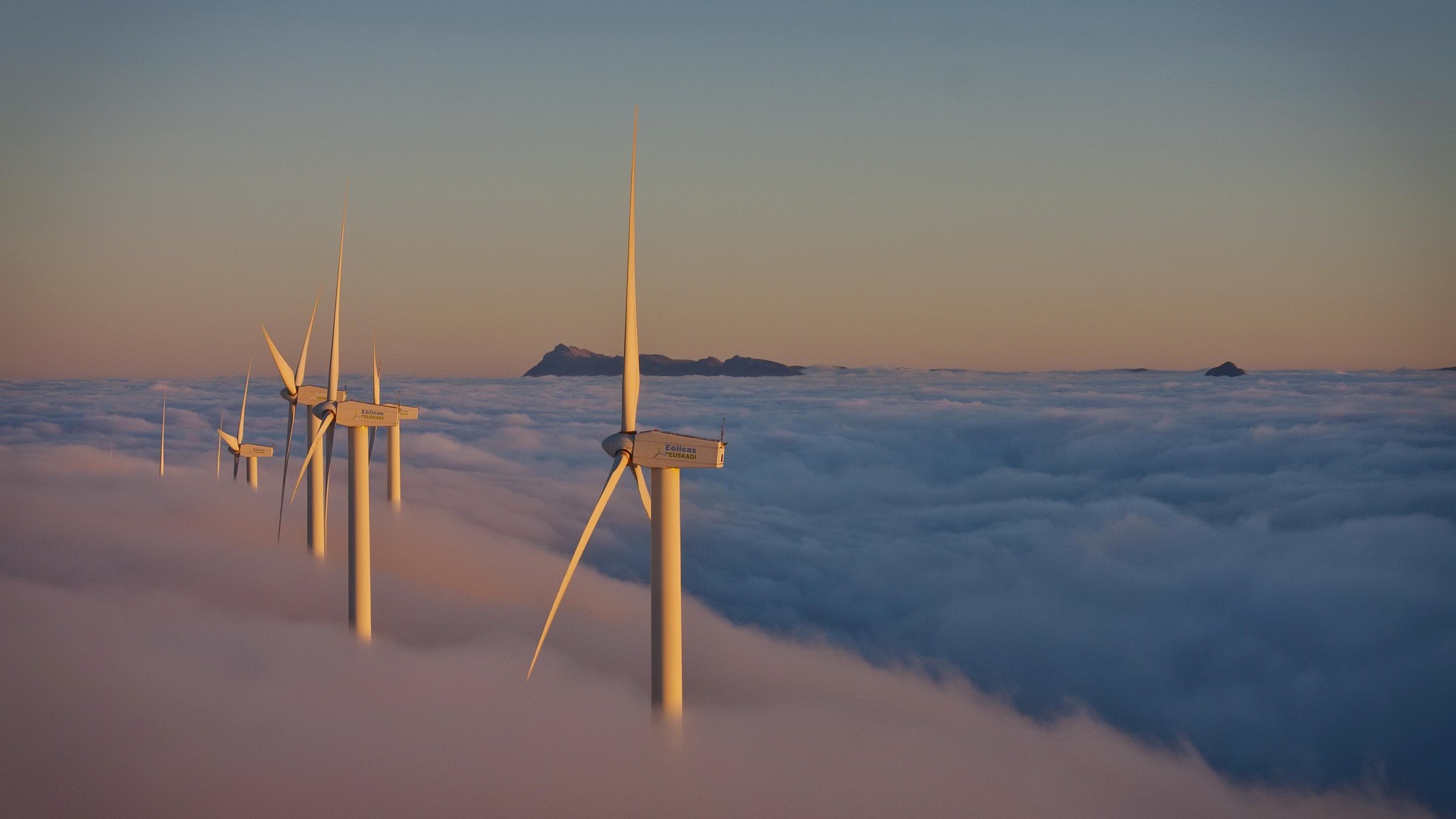 Wind turbines above a sea of clouds at sunset HD Wallpaper