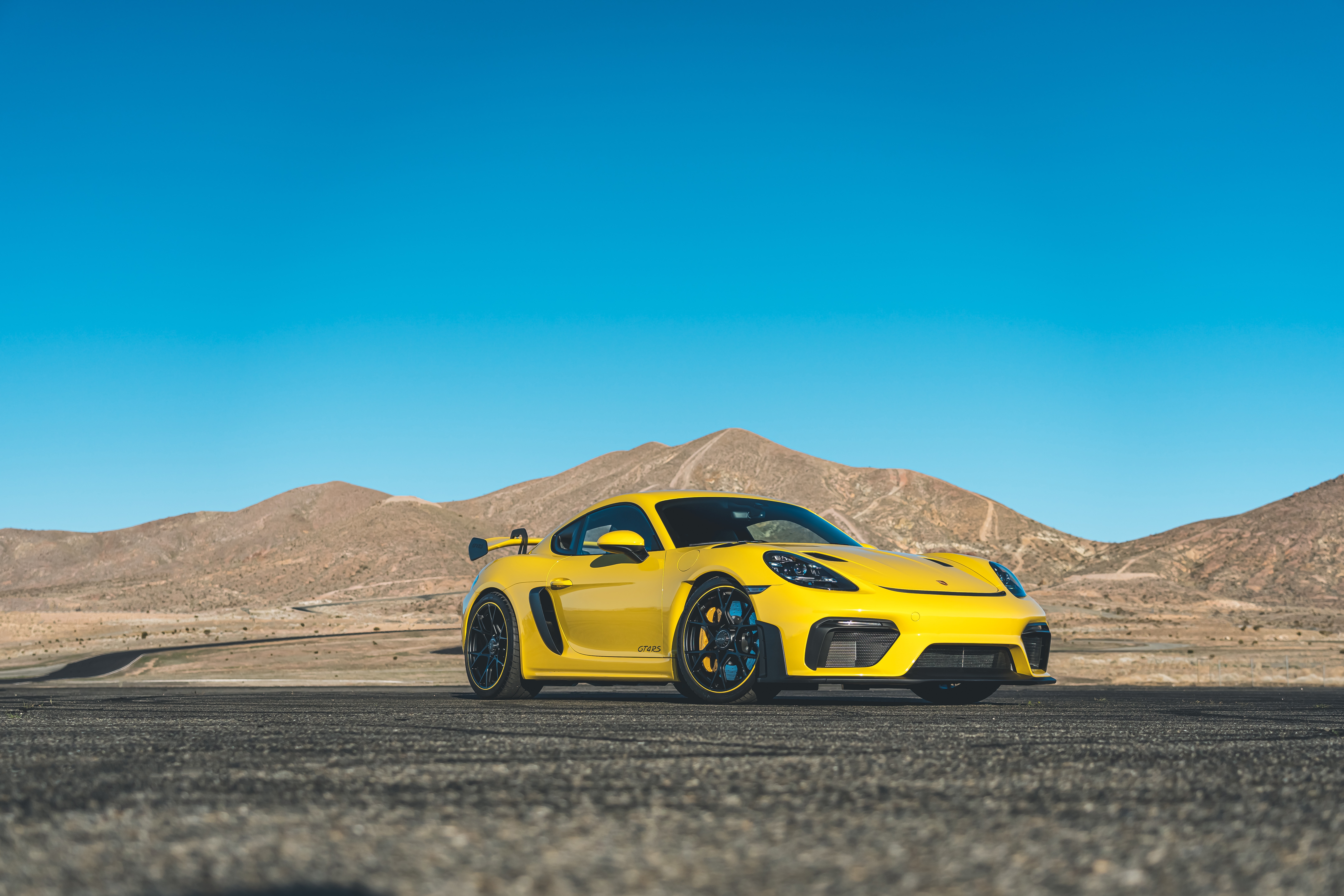 Yellow Porsche 718 Cayman GT4 RS in desert landscape HD Wallpaper