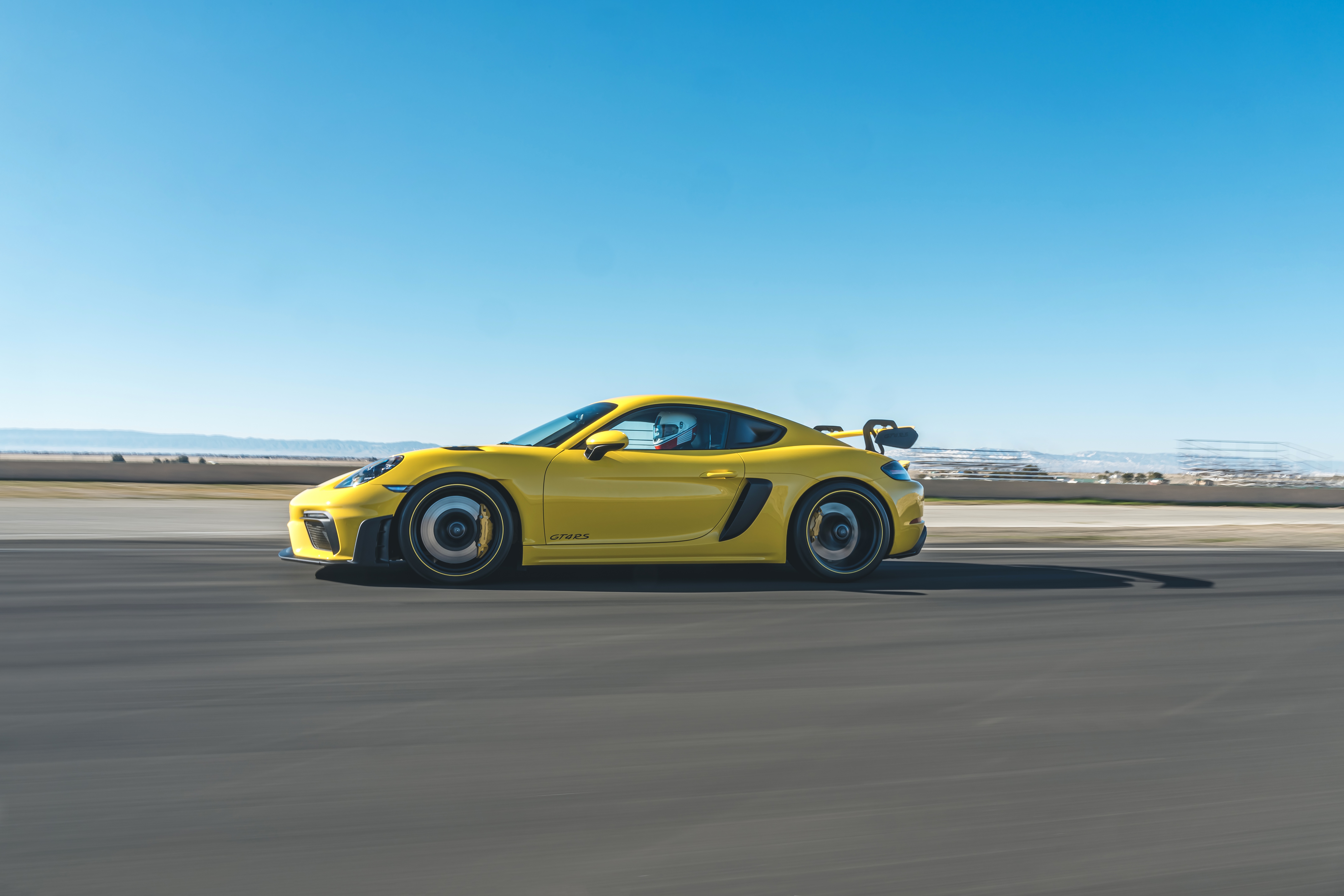 Yellow Porsche 718 Cayman GT4 on a Racetrack HD Wallpaper