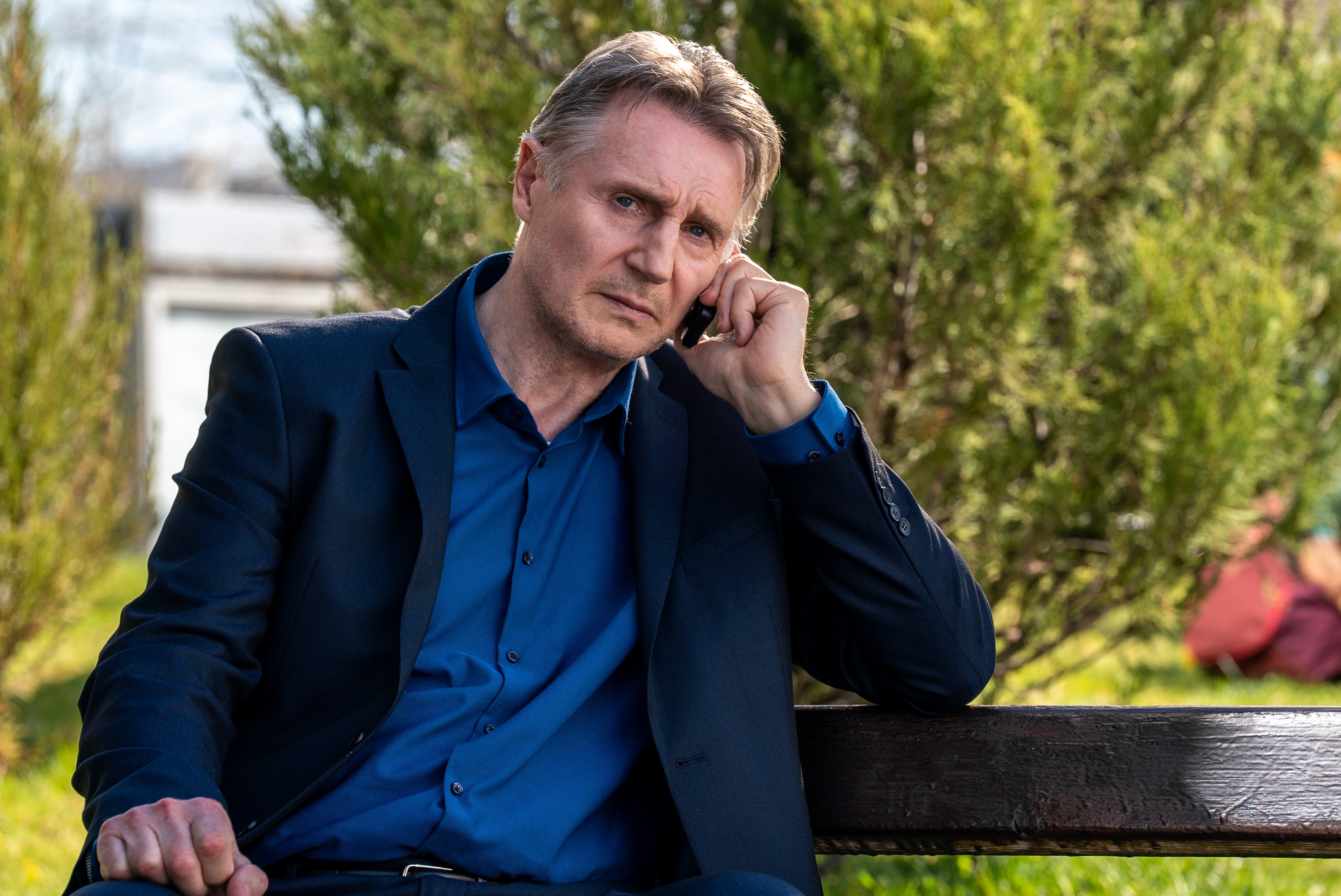 Liam Neeson on a phone call outdoors HD Wallpaper