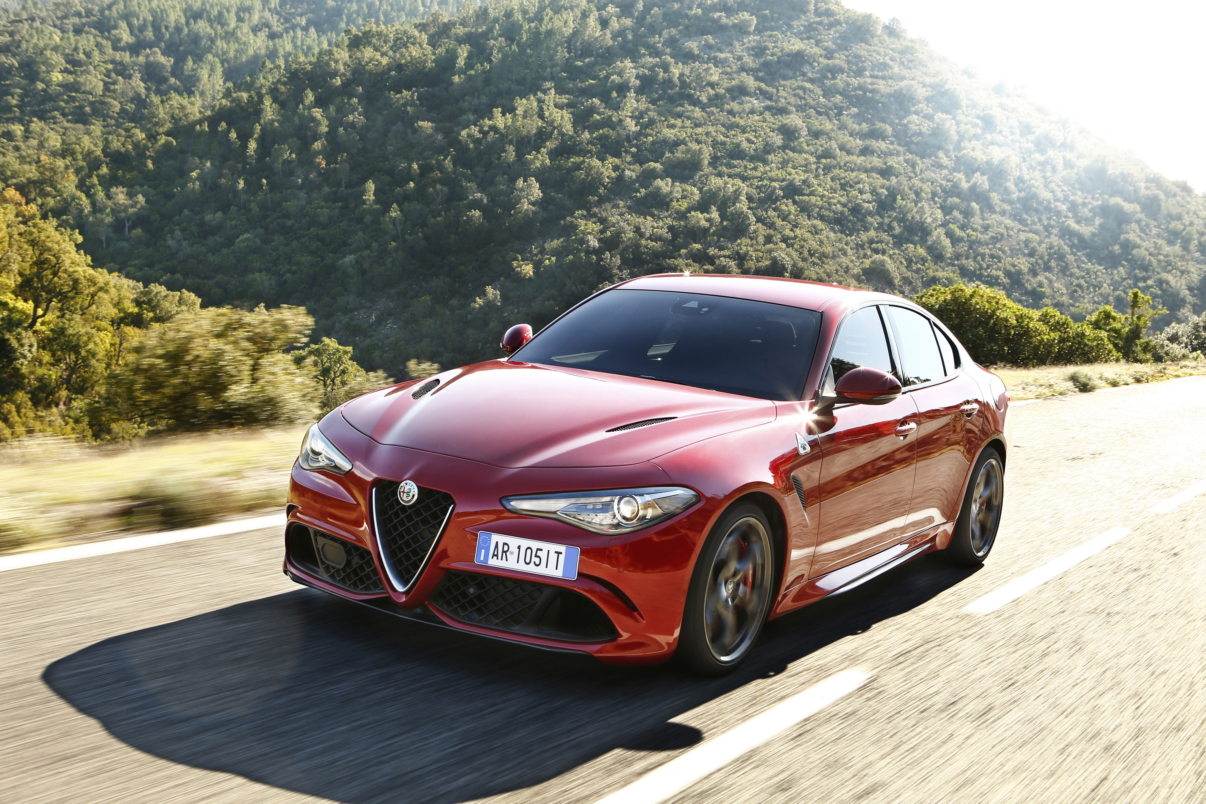 Red Alfa Romeo Giulia driving on a road HD Wallpaper