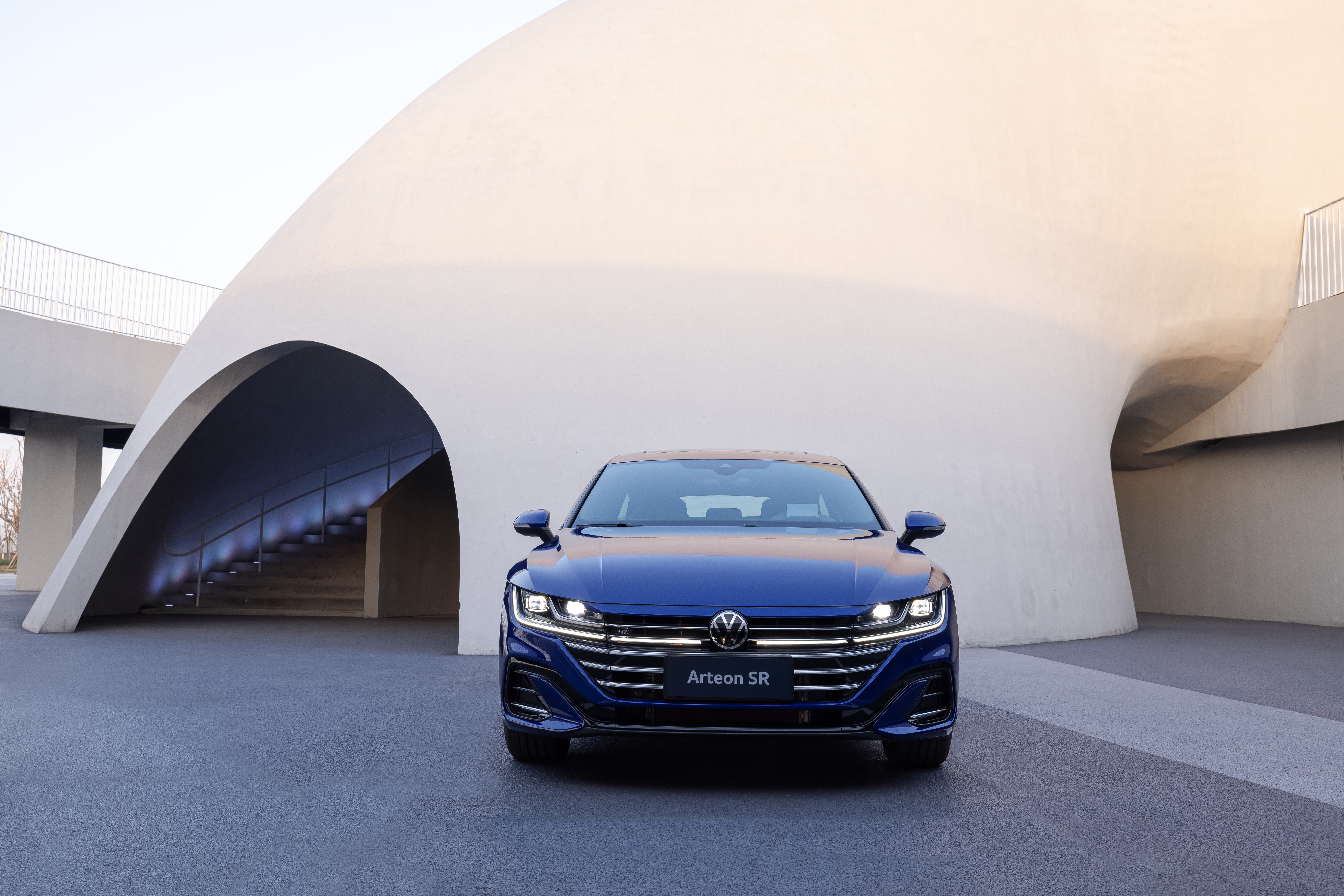Blue Volkswagen Arteon SR parked in front of a modern building HD Wallpaper
