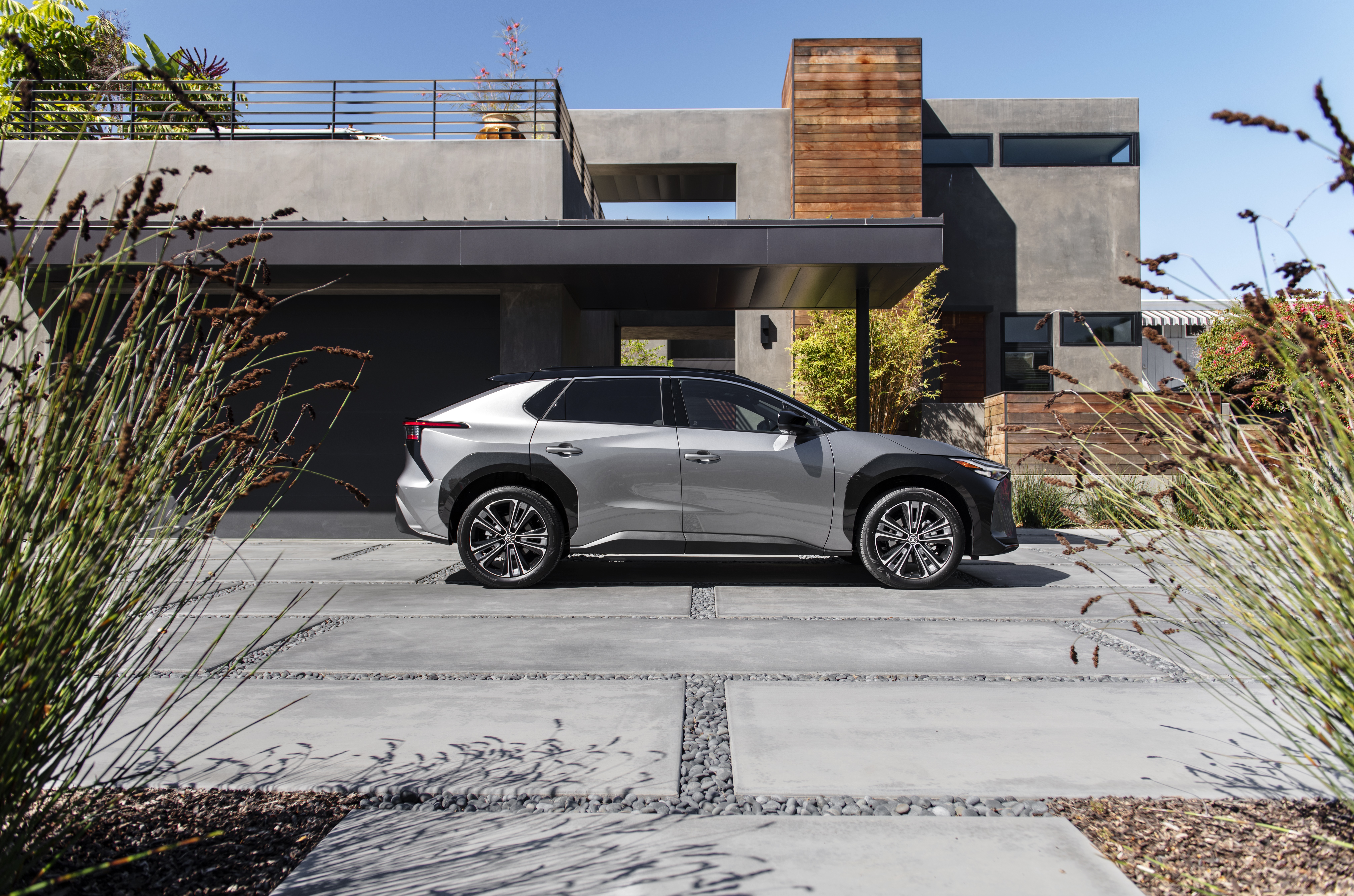 Toyota BZ4X parked in front of a modern house HD Wallpaper