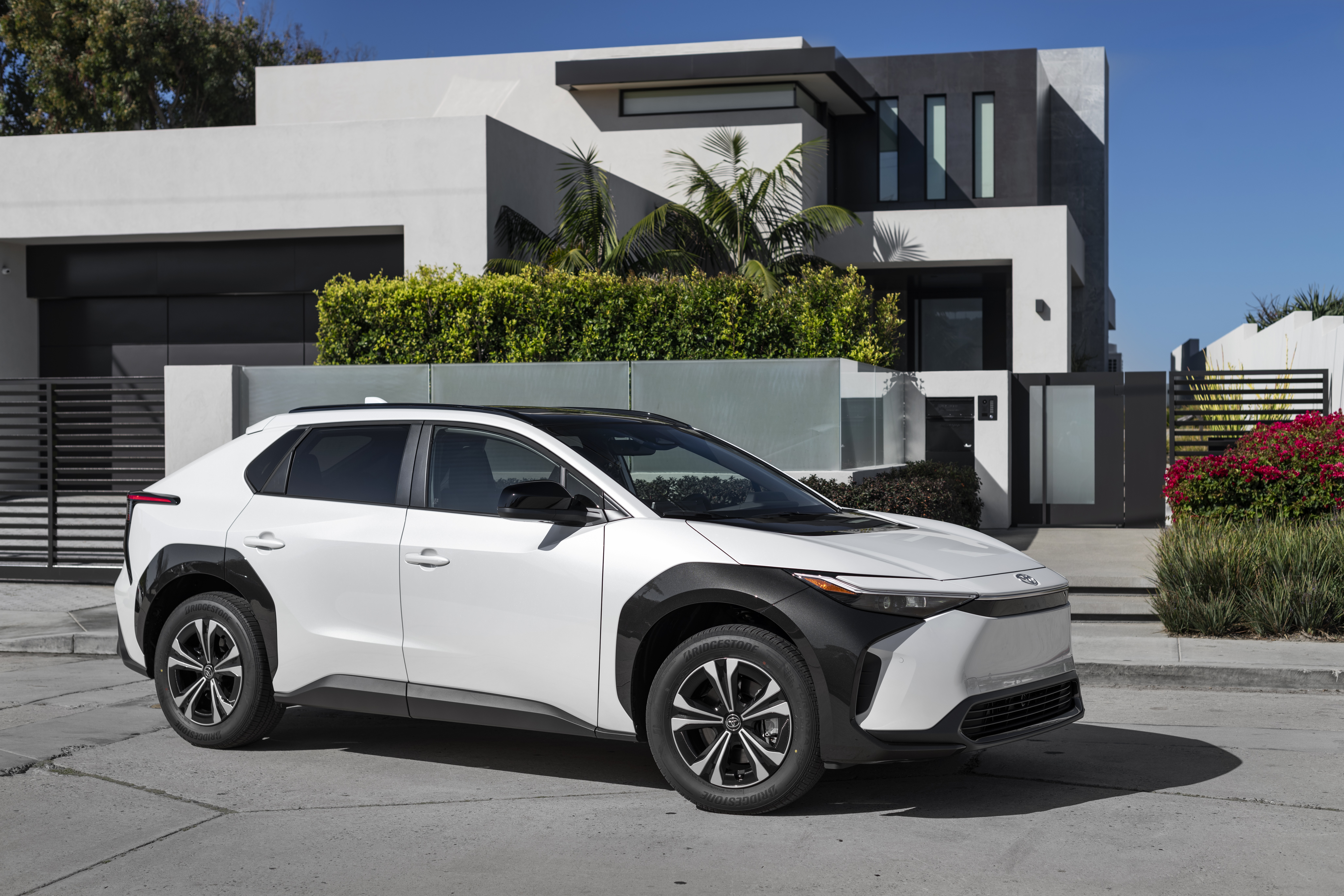 White Toyota BZ4X parked in front of a modern house HD Wallpaper