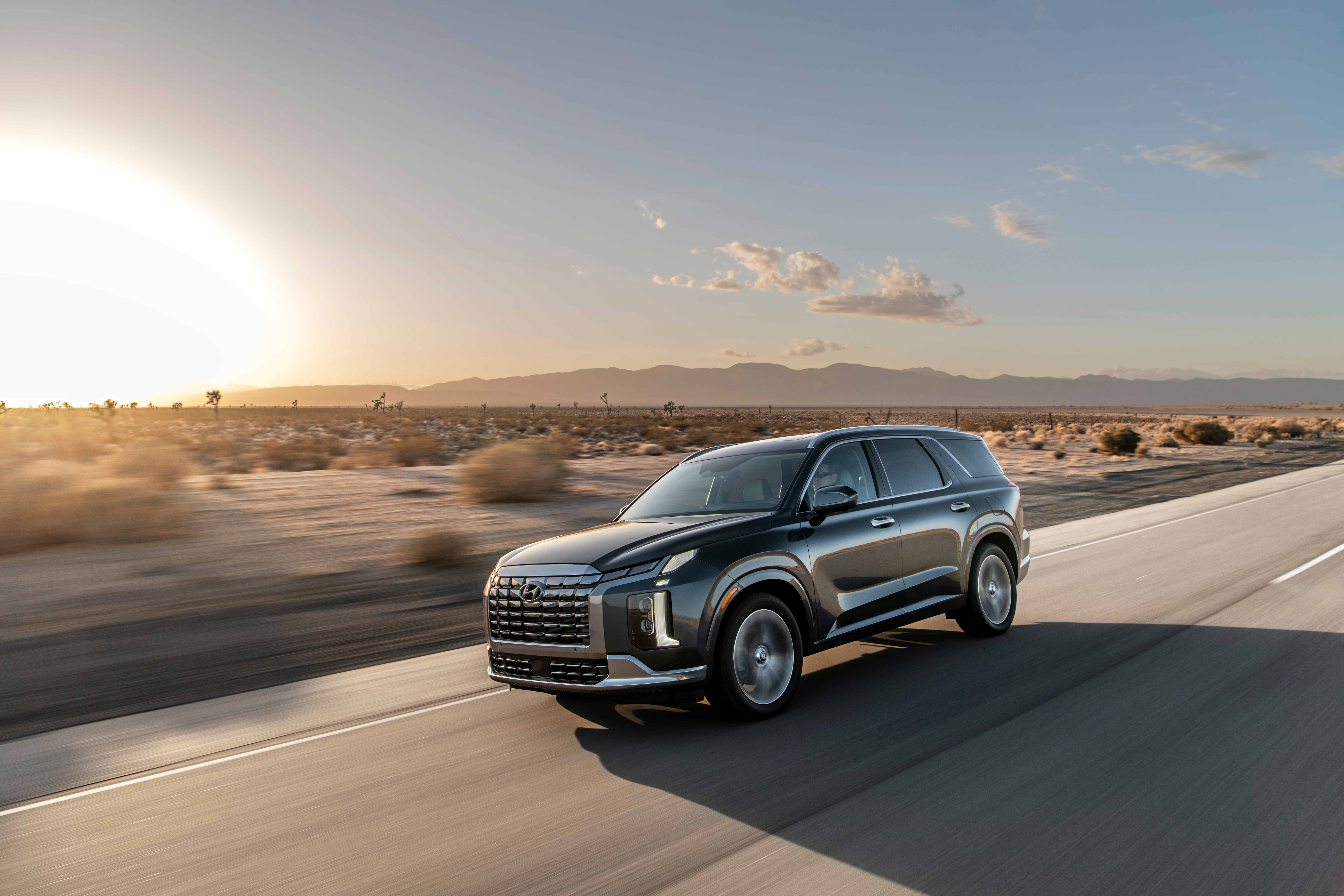 Hyundai Palisade driving on a desert highway at sunset HD Wallpaper