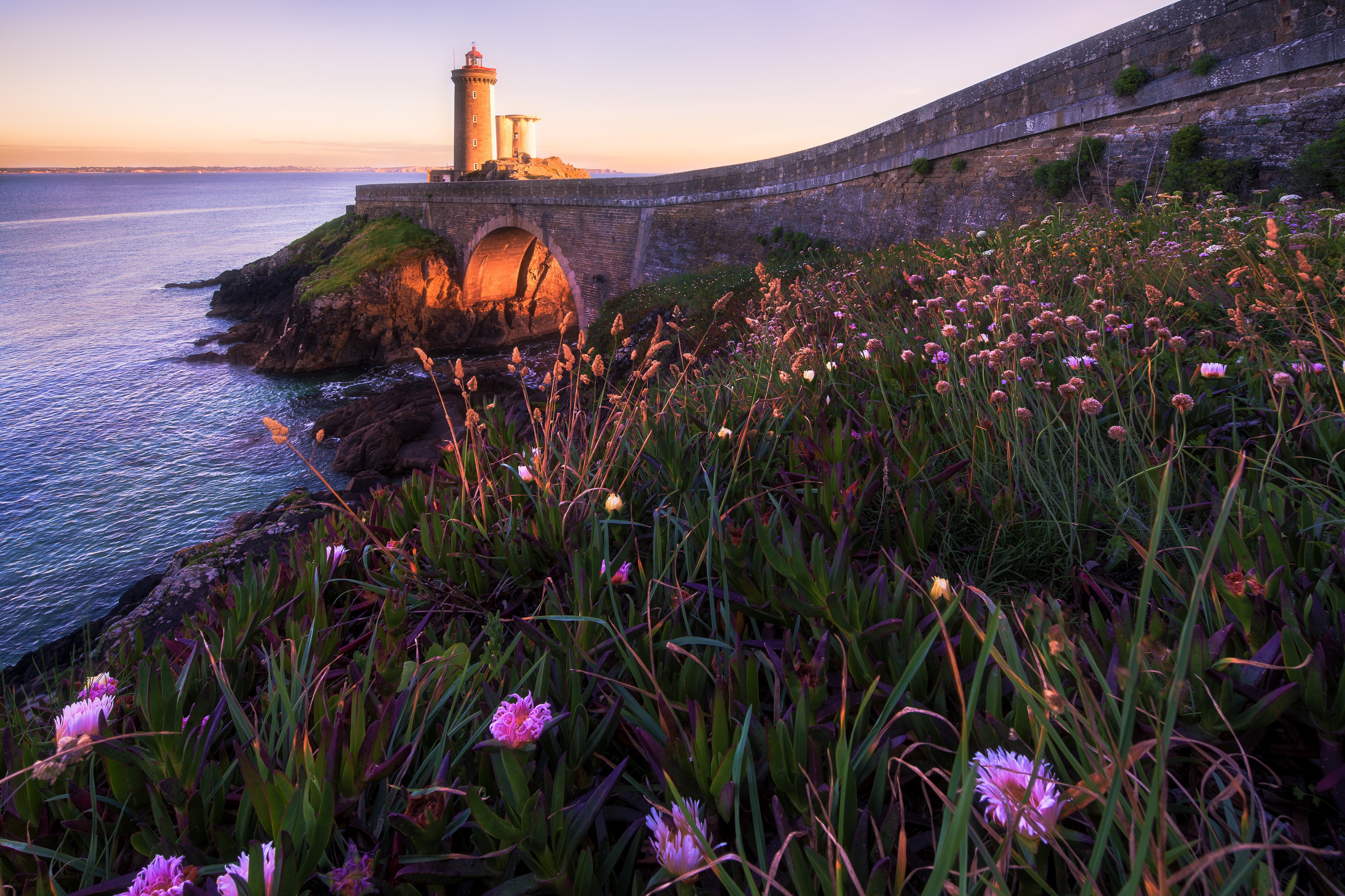 Lighthouse on a cliff overlooking the sea at sunset HD Wallpaper