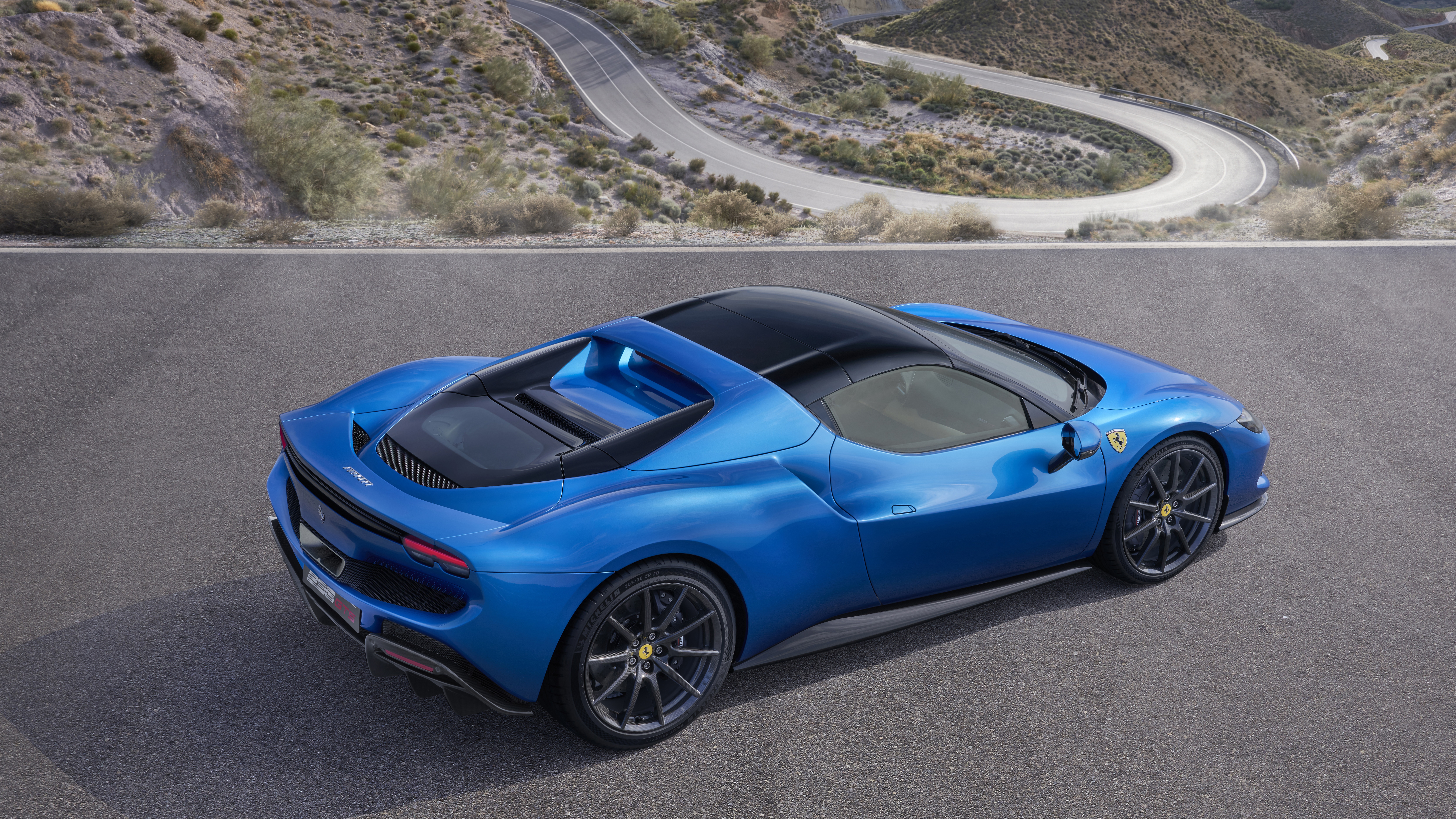 Blue Ferrari 296 GTS on a winding road HD Wallpaper