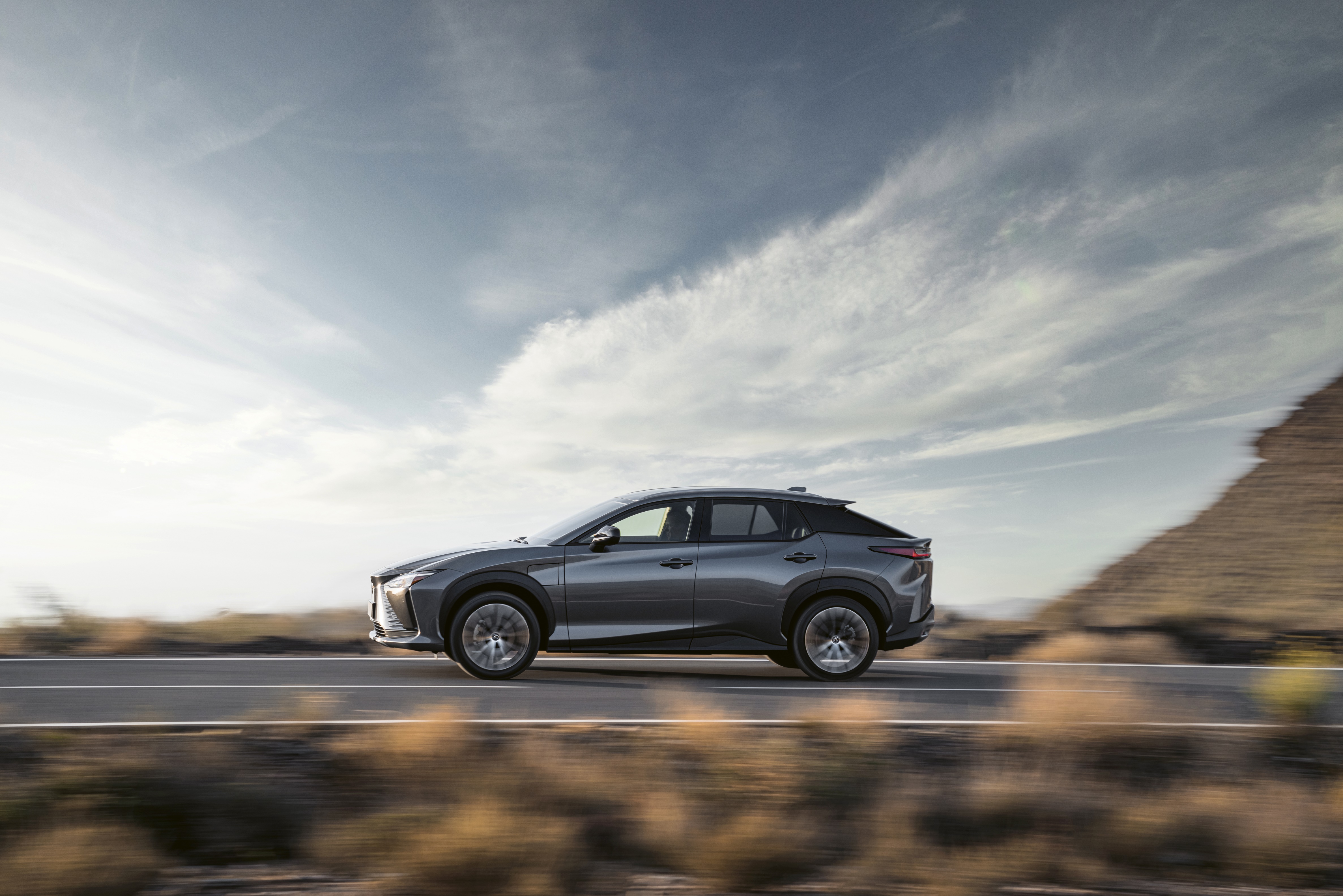 Lexus RZ 450e driving on a road HD Wallpaper