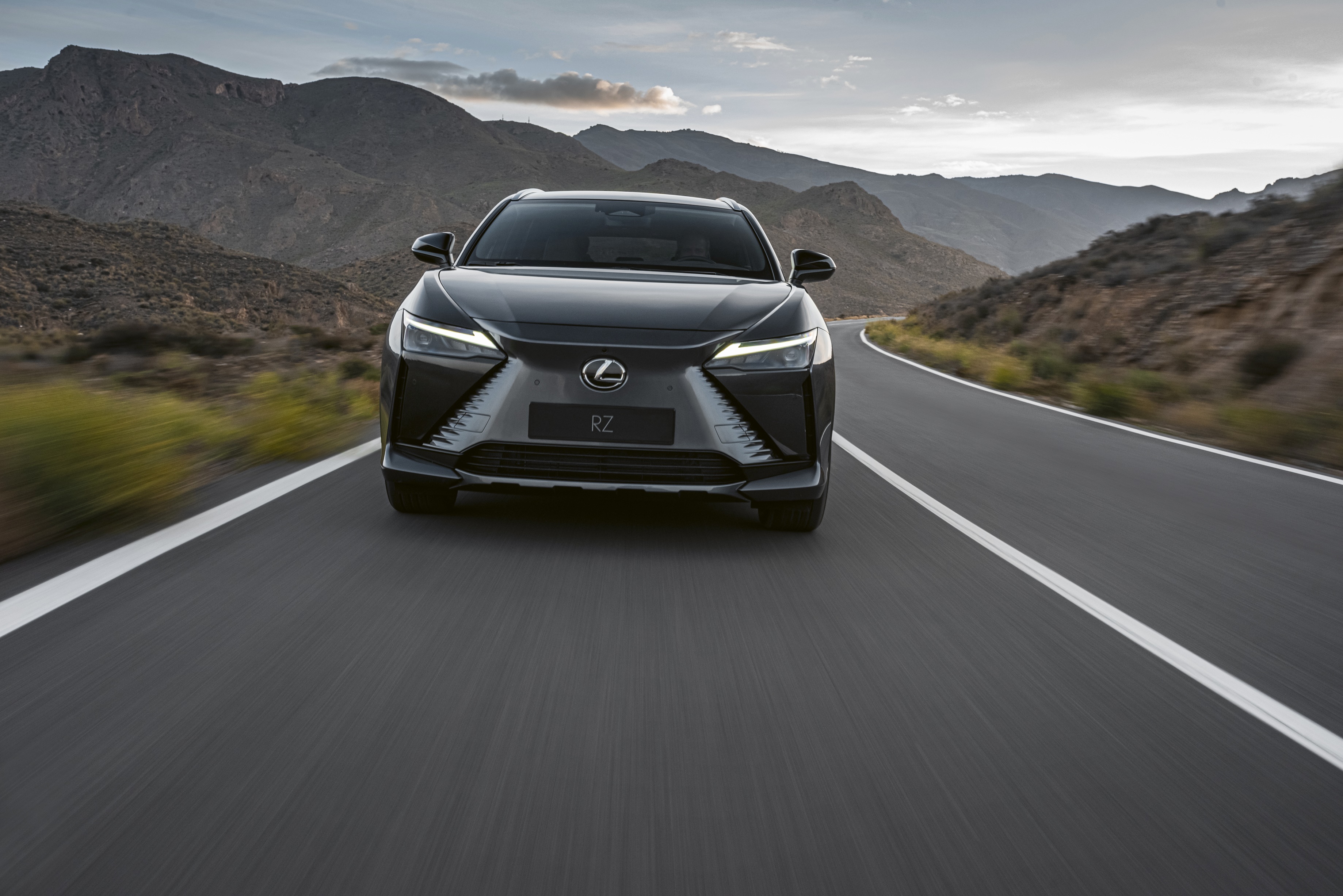 Lexus RZ 450e driving on a mountain road HD Wallpaper
